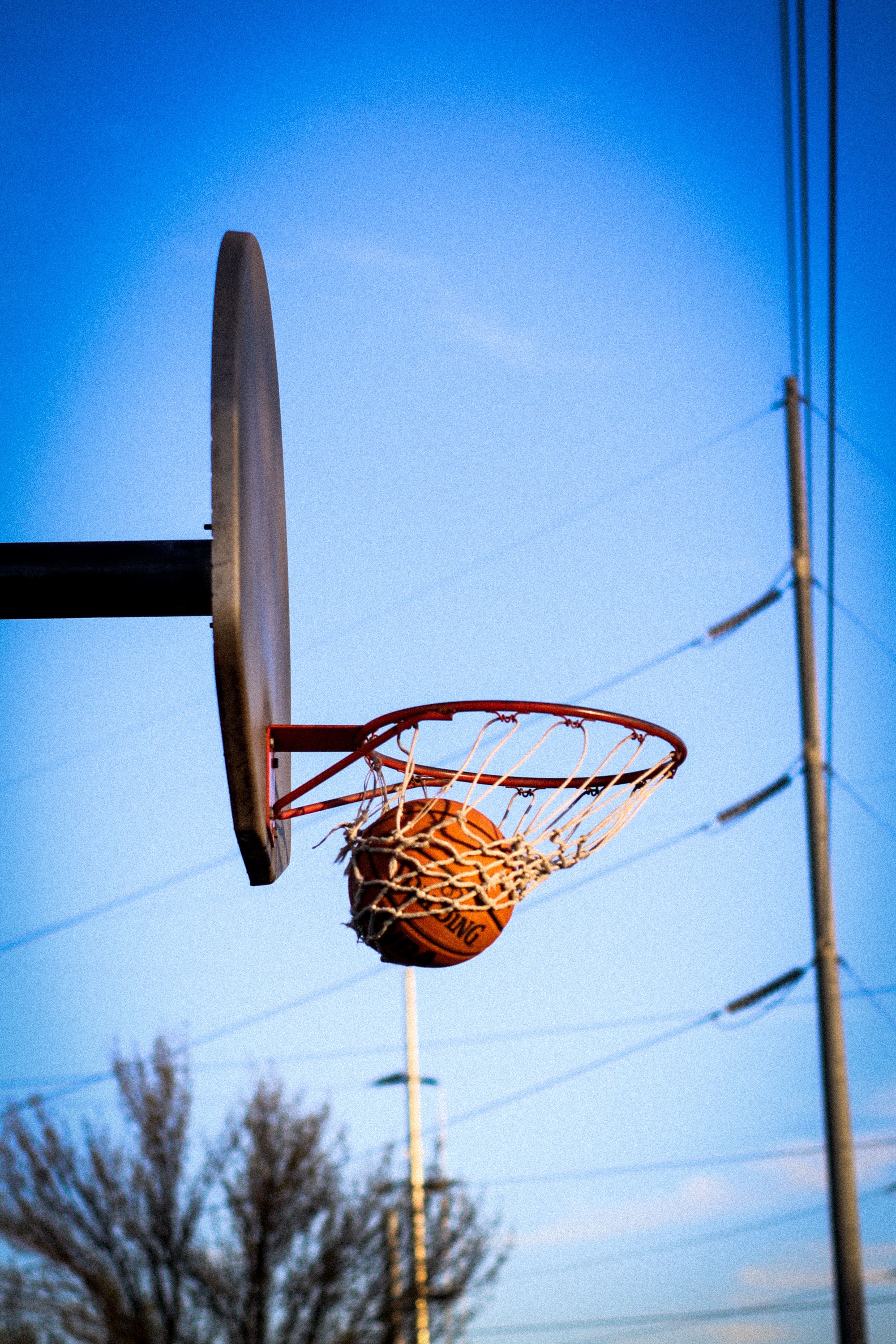 A basketball in the air, in the process of going through the hoop. - Basketball