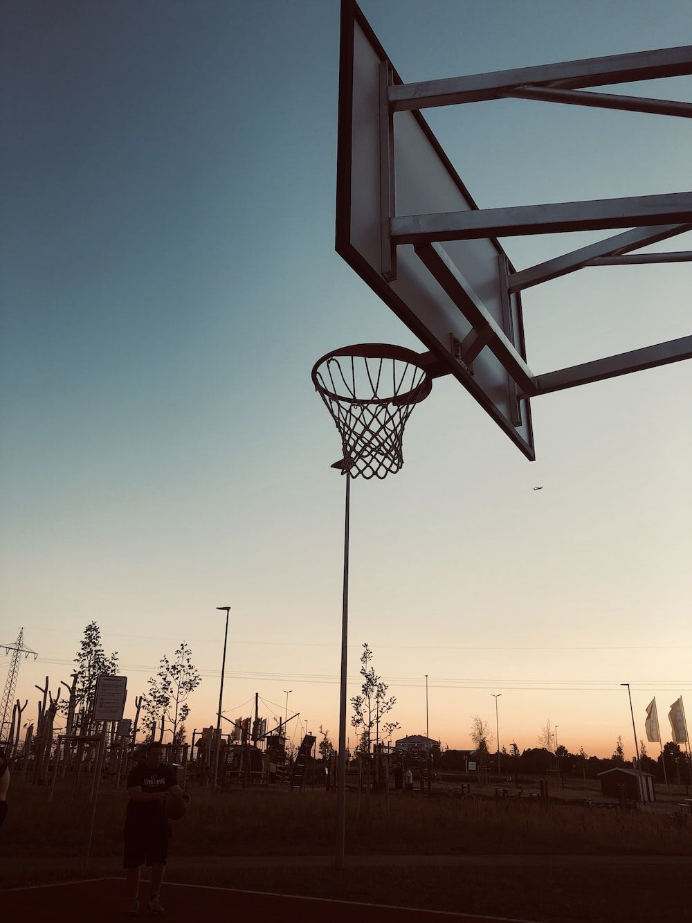 A basketball hoop on top of an outdoor court - Basketball