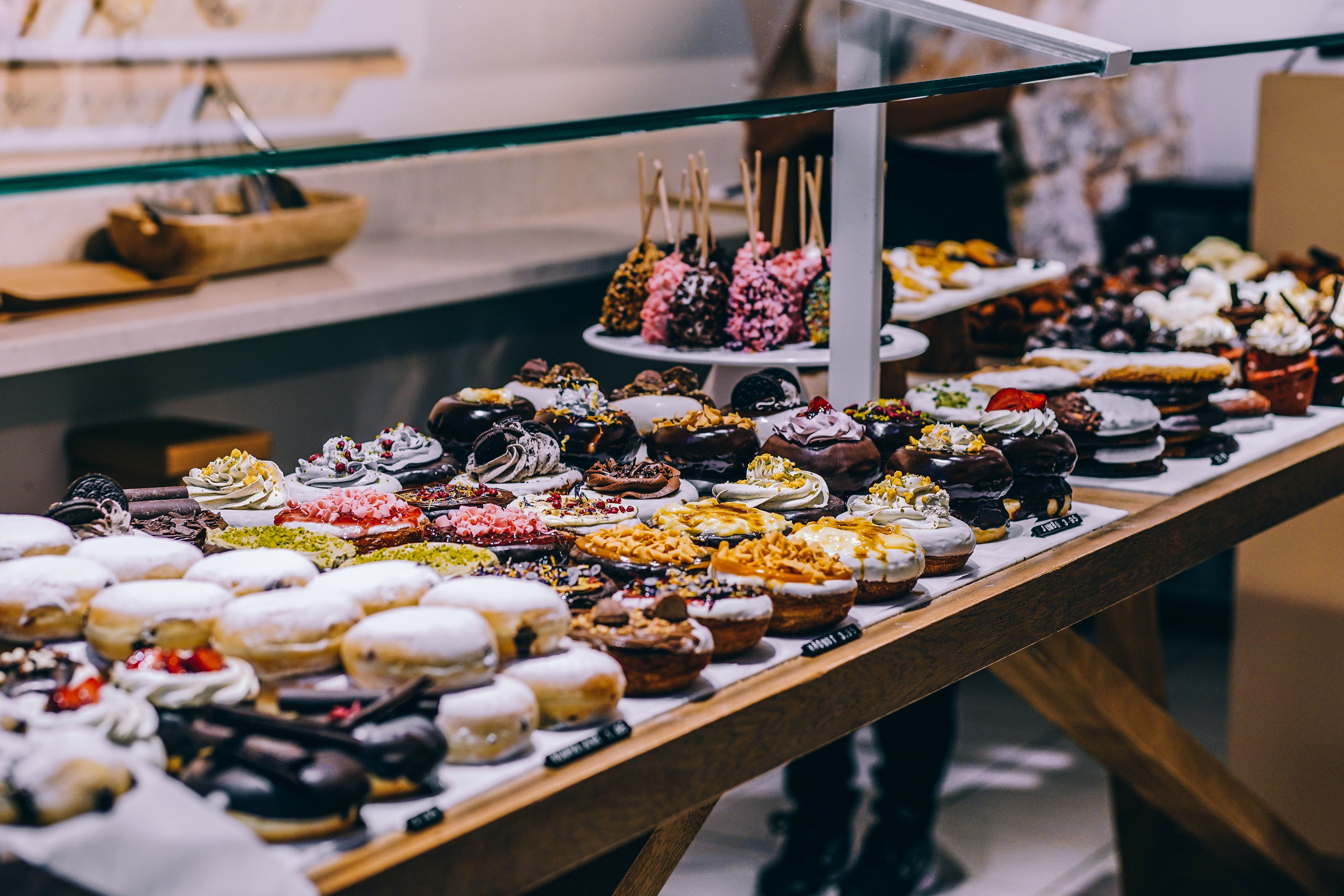 A table full of various donuts with different flavors and toppings. - Bakery