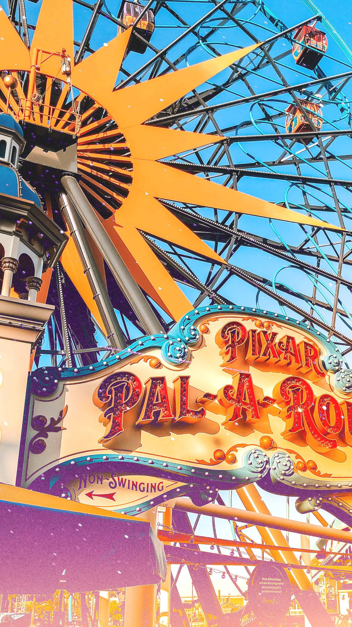 A colorful sign for the Pixar Pal-A-Round, a Ferris wheel, in front of a blue sky. - Disneyland