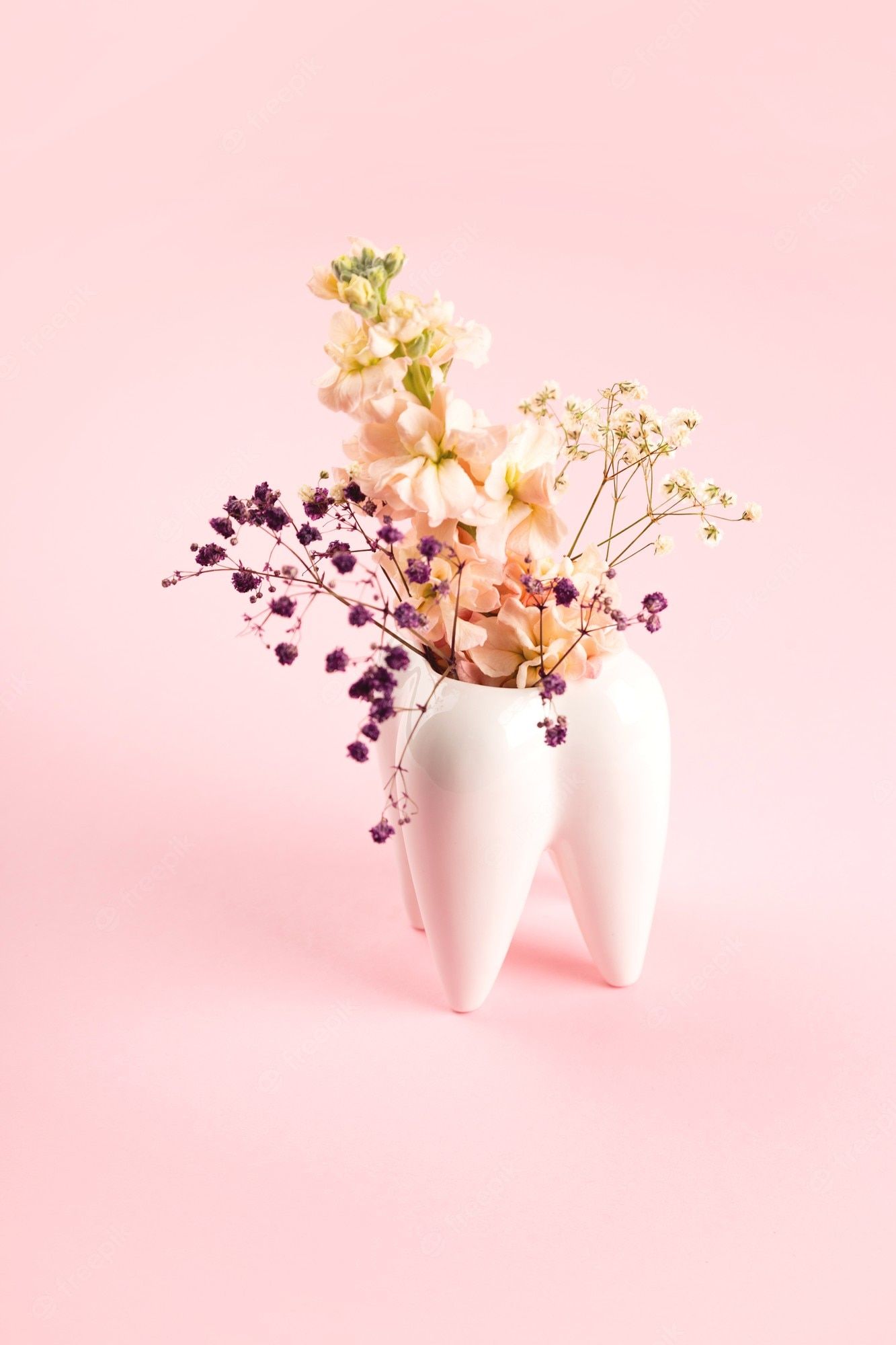 Premium Photo. White big tooth vase with flowers on pink background work and orthodontist dentist aesthetics