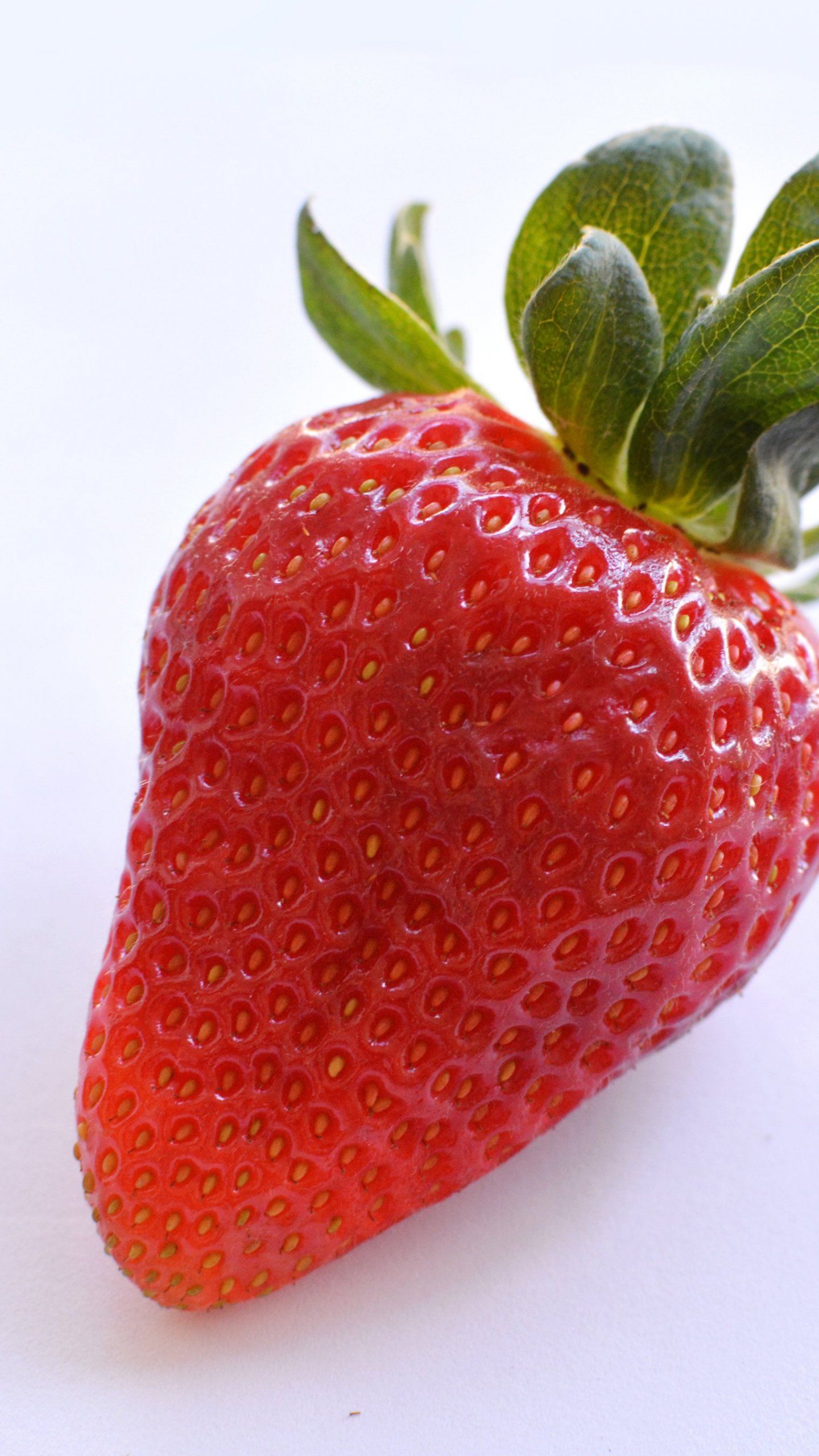 A strawberry sitting on top of white surface - Strawberry