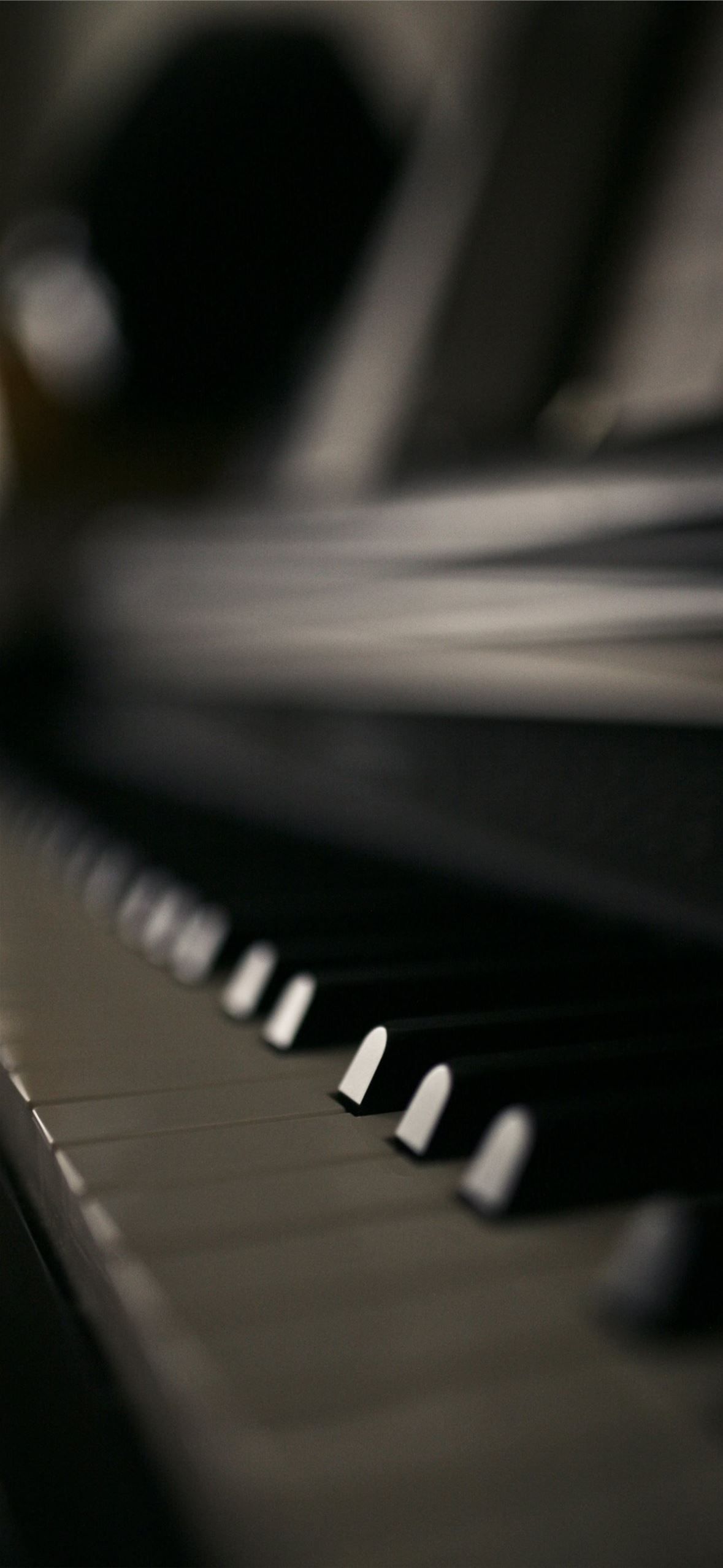 A close up of a piano keyboard, with a hand on the background. - Piano