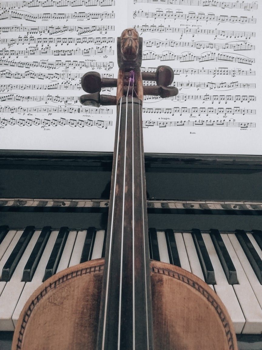 A violin is sitting next to the piano - Piano