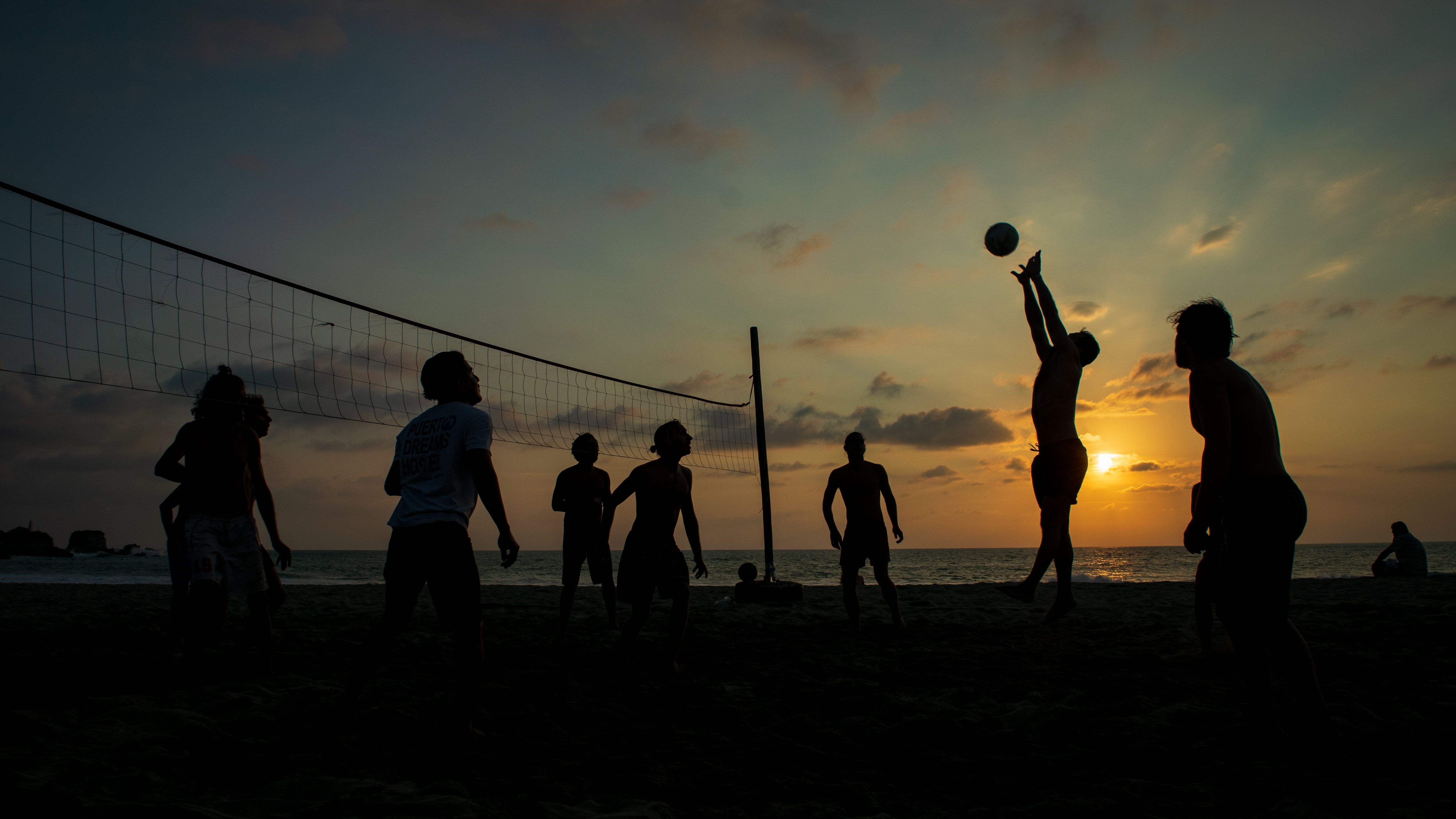 A group of people playing volleyball on the beach - Volleyball