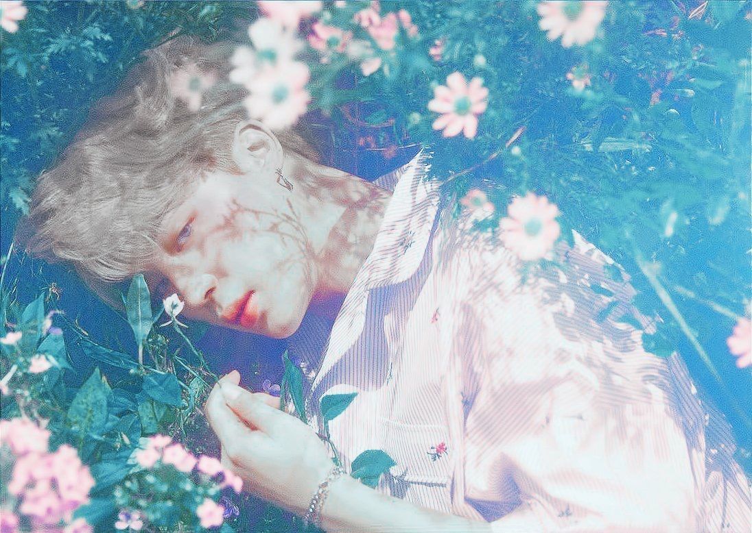 A person laying in a field of flowers - Jimin