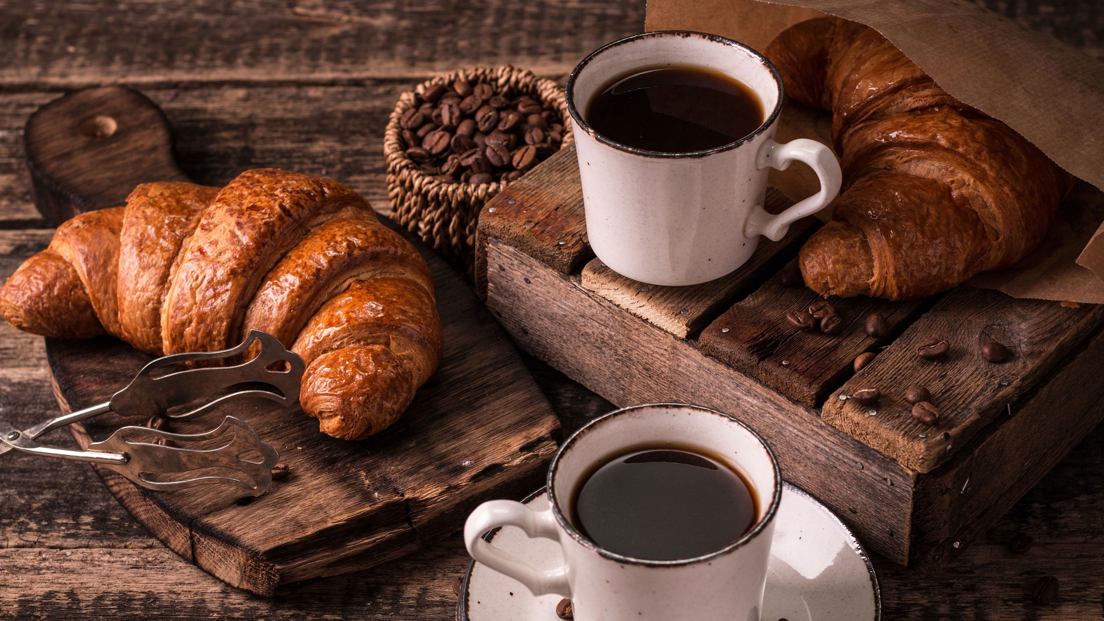 Two cups of coffee and three croissants on a wooden table. - Coffee