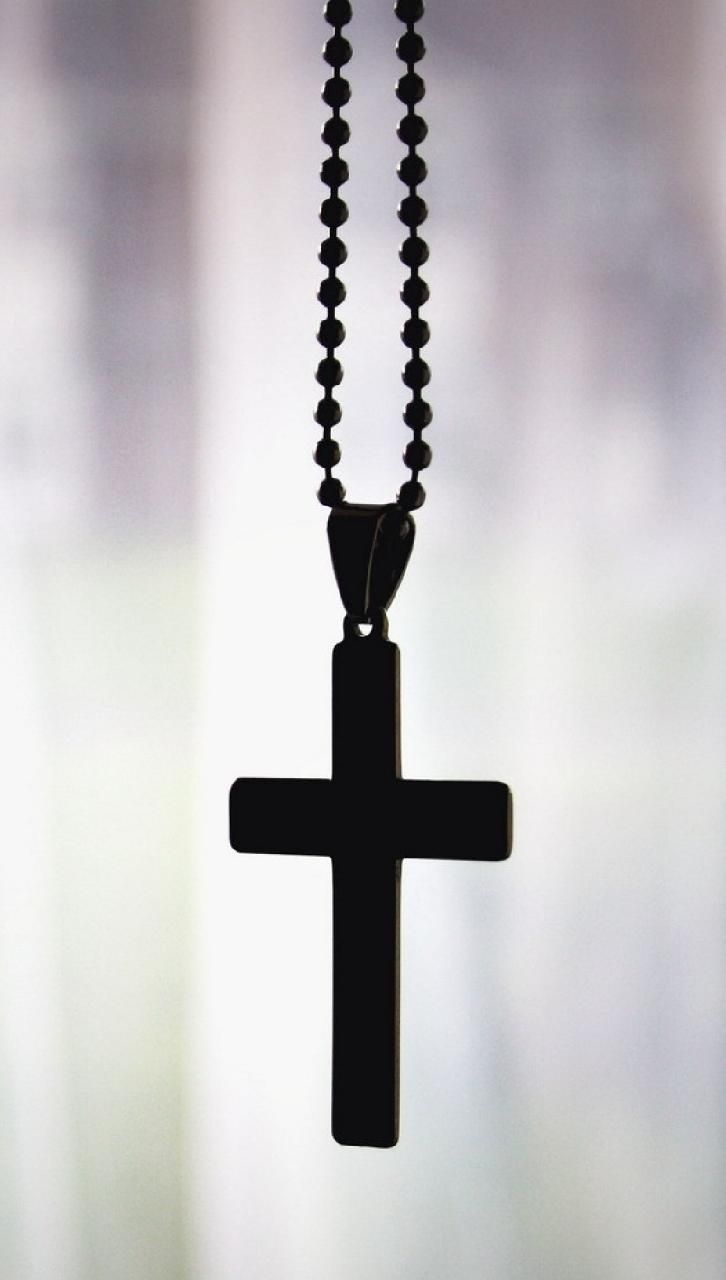 A black cross hanging from the neck of someone - Cross