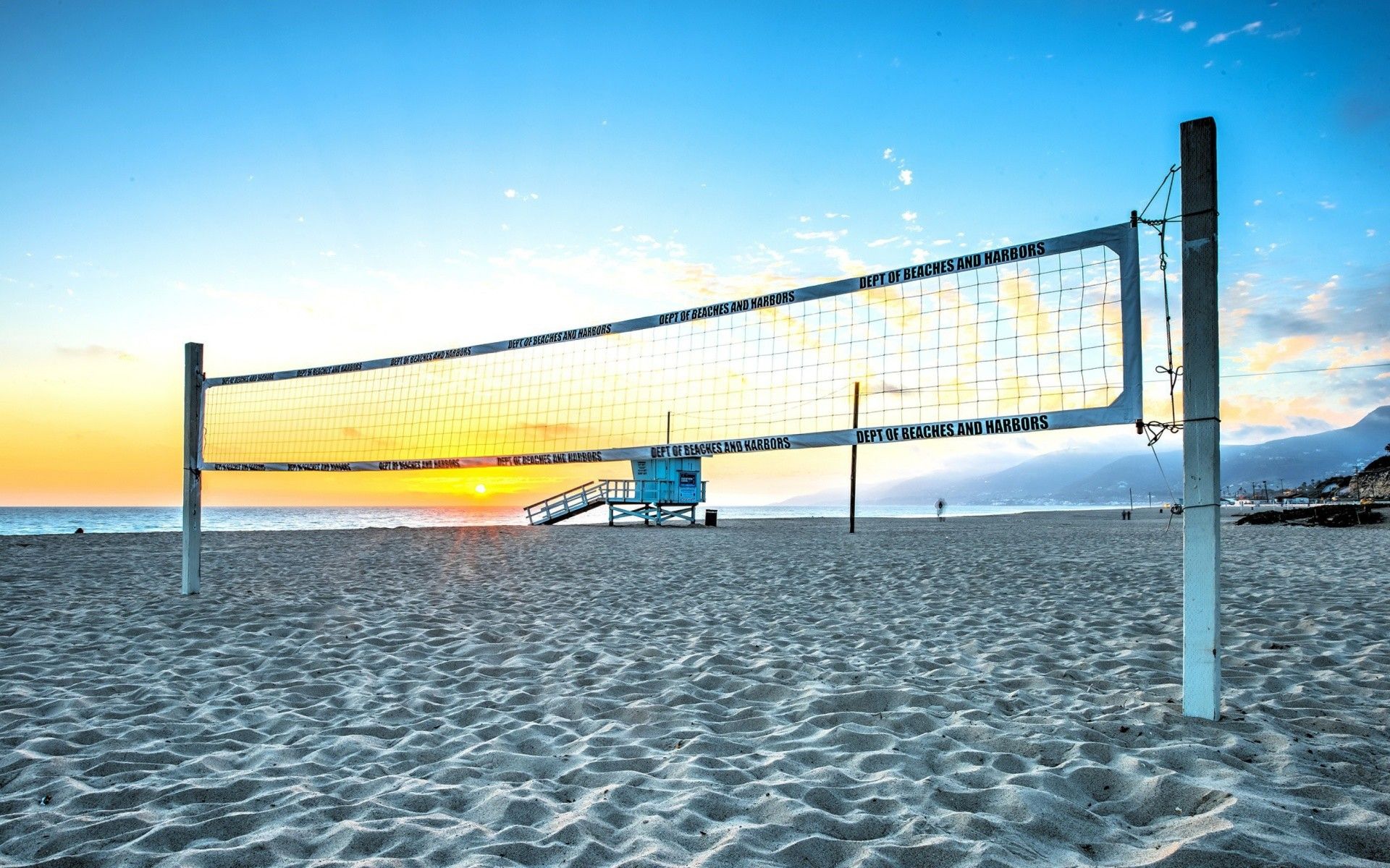 A volleyball net on the beach with sunset in background - Volleyball