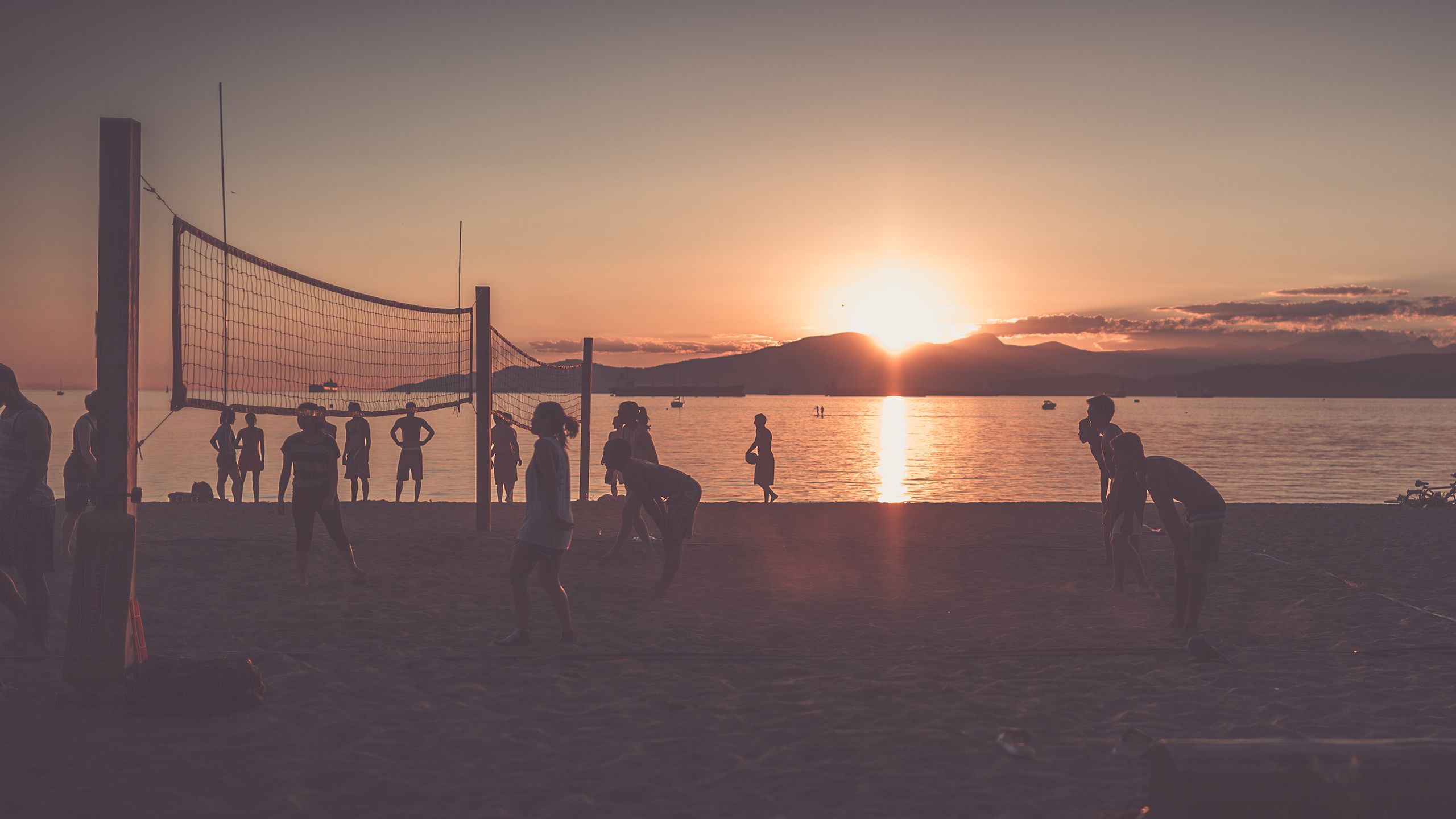 People playing volleyball on the beach at sunset. - Volleyball