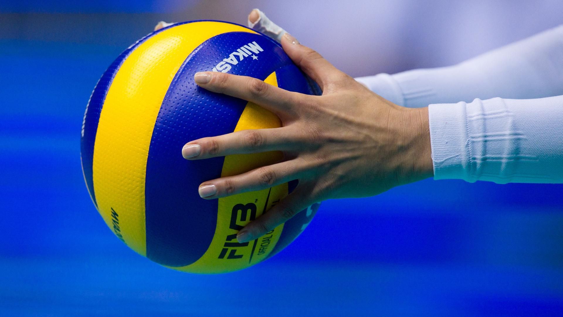 A person holding onto the ball with their hand - Volleyball