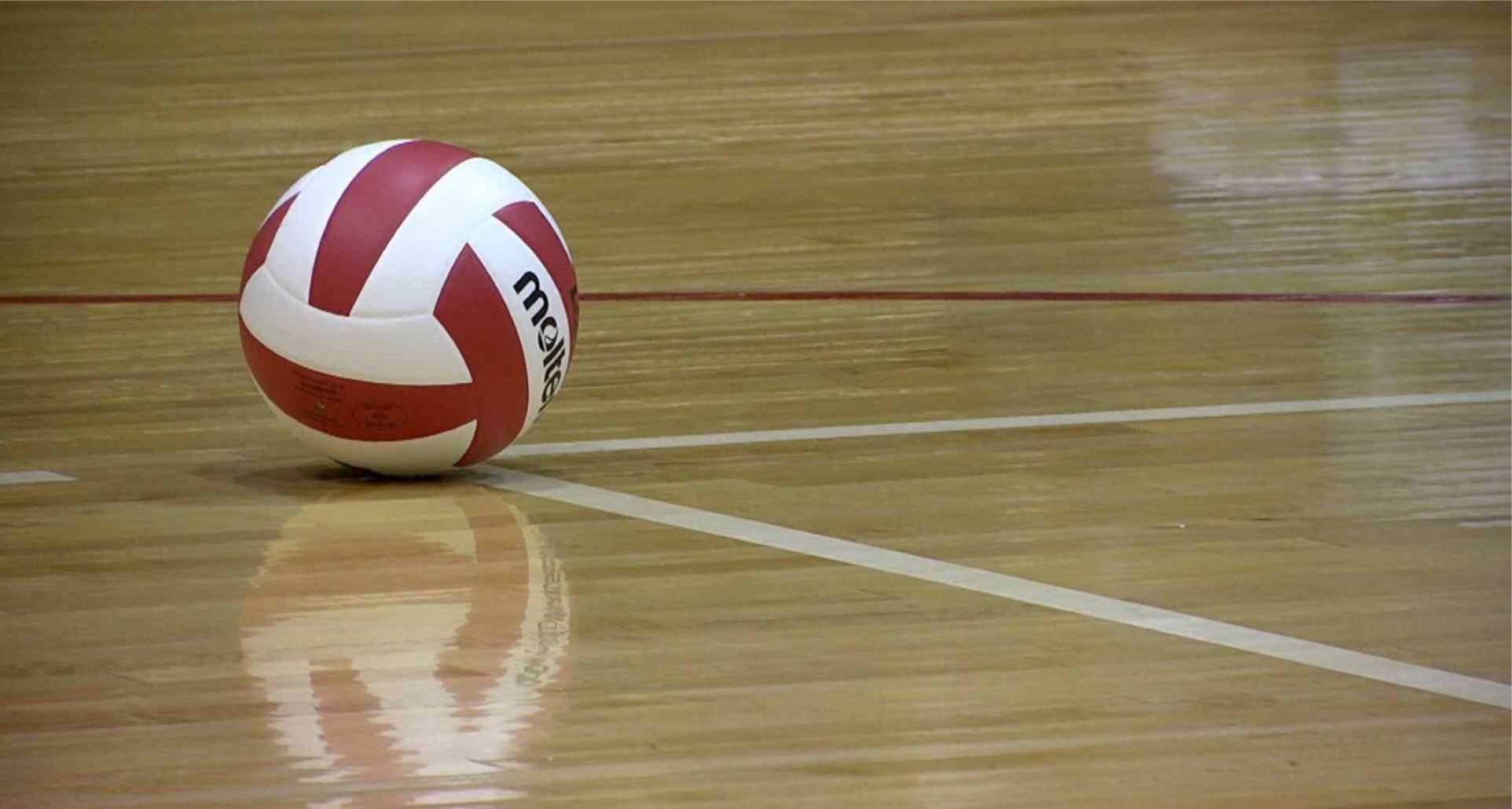 A volleyball sitting on the floor of an indoor court - Volleyball