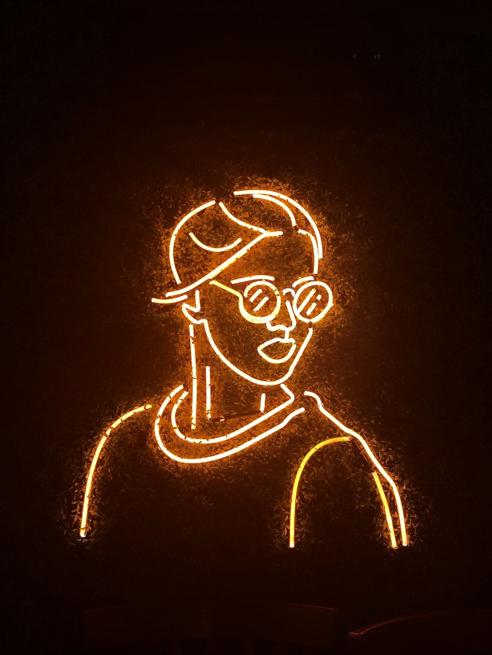 A neon sign of a man with glasses. - Neon orange
