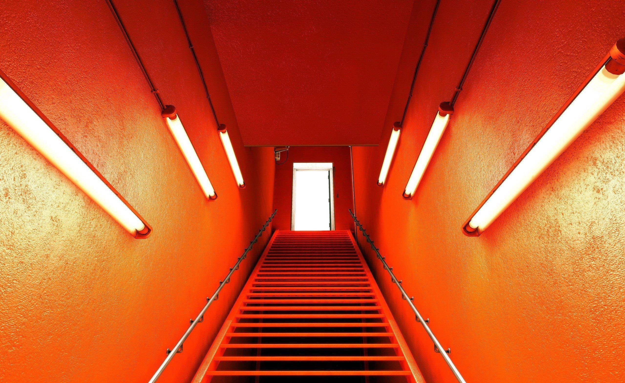 A long orange staircase with a door at the end. - Orange, neon orange