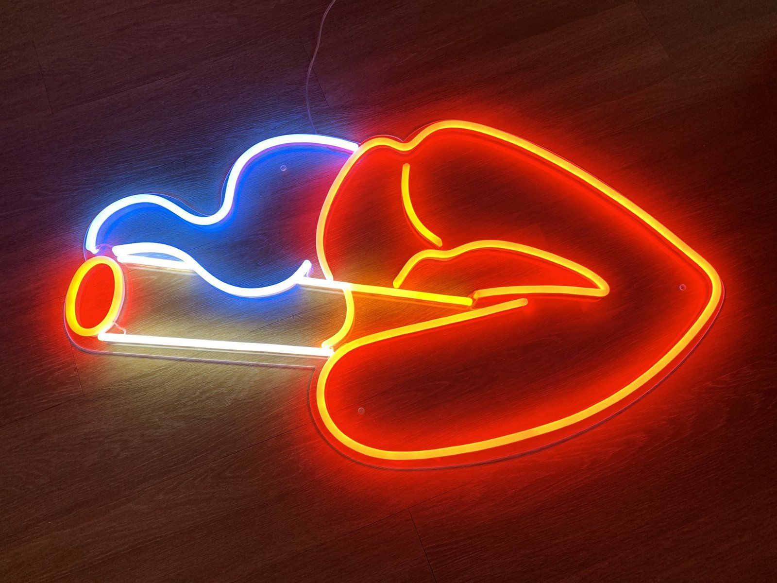 A neon sign of a pair of lips in red and blue. - Neon orange