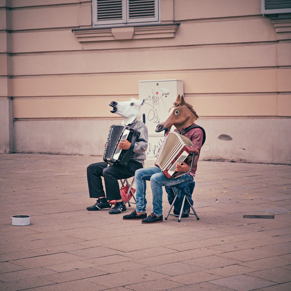 A man and woman sitting on the street playing instruments - Funny