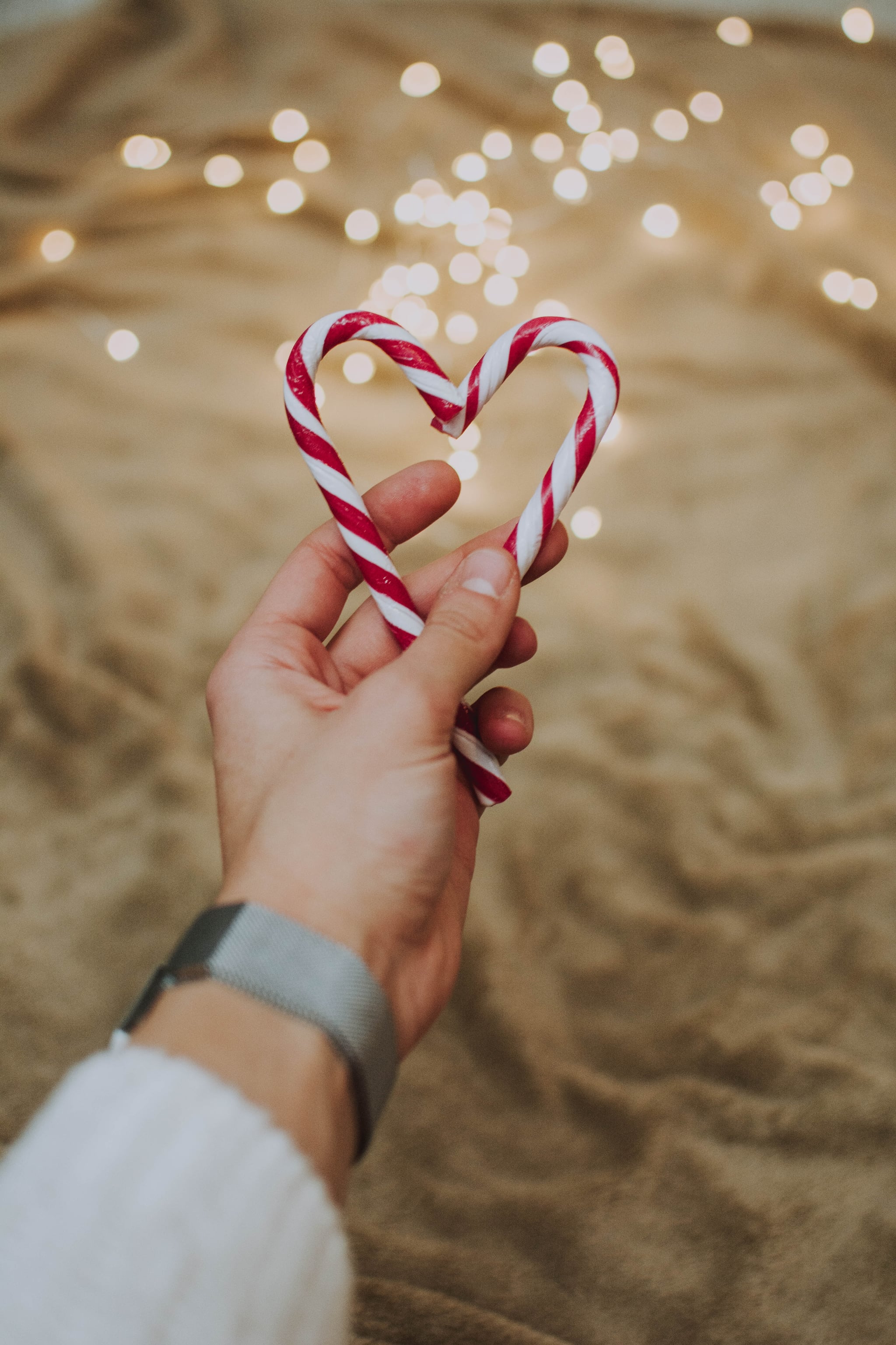 A person holding two candy canes in the shape of a heart. - Candy cane, candy