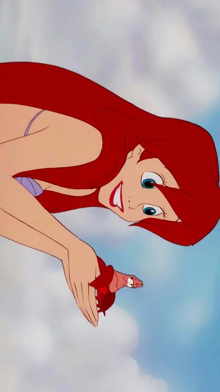 Ariel from The Little Mermaid, wearing a red dress and smiling as she looks down at a seashell in her hand. - Ariel