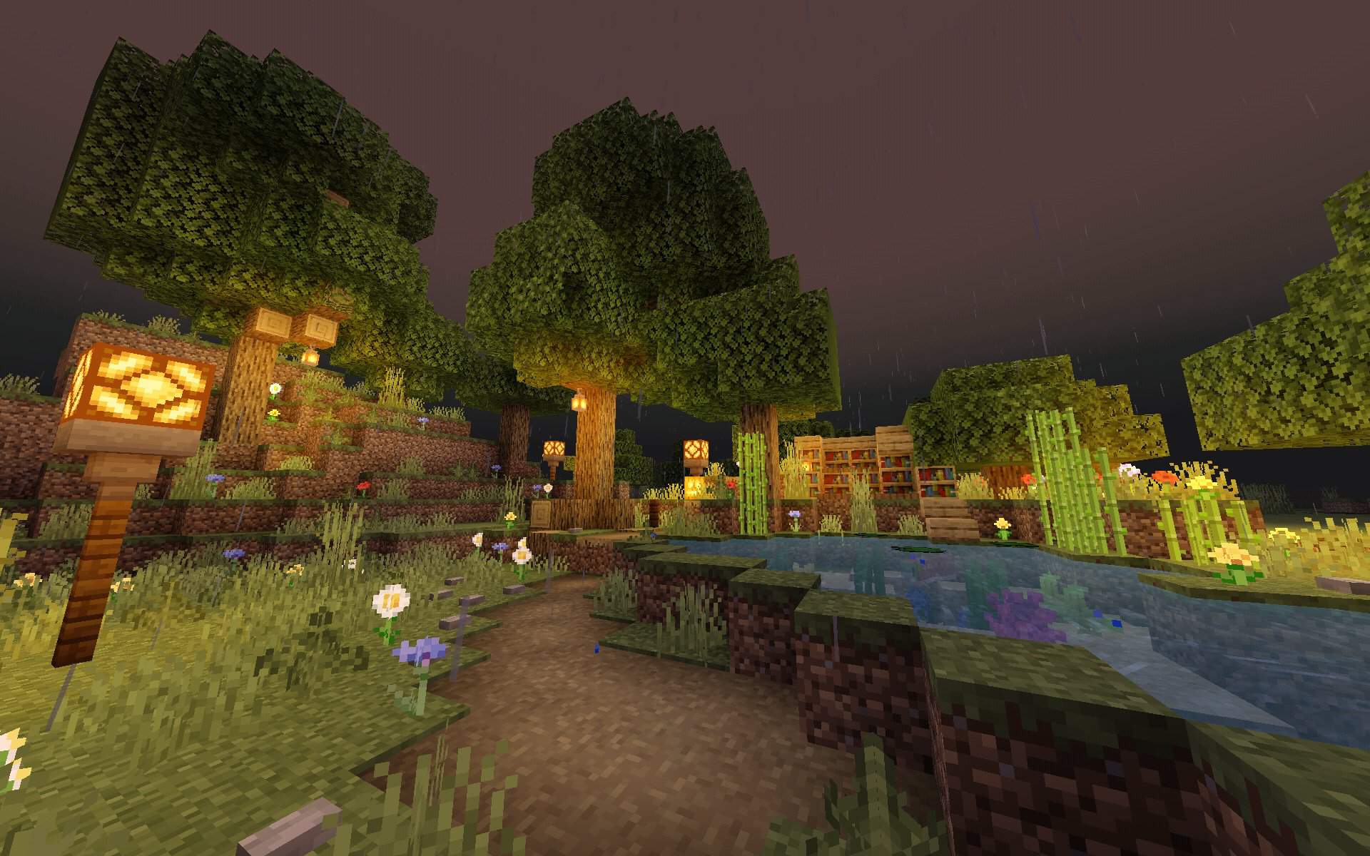 A screenshot of a Minecraft world at night, with a house built around a tree, and a pond nearby. - Minecraft