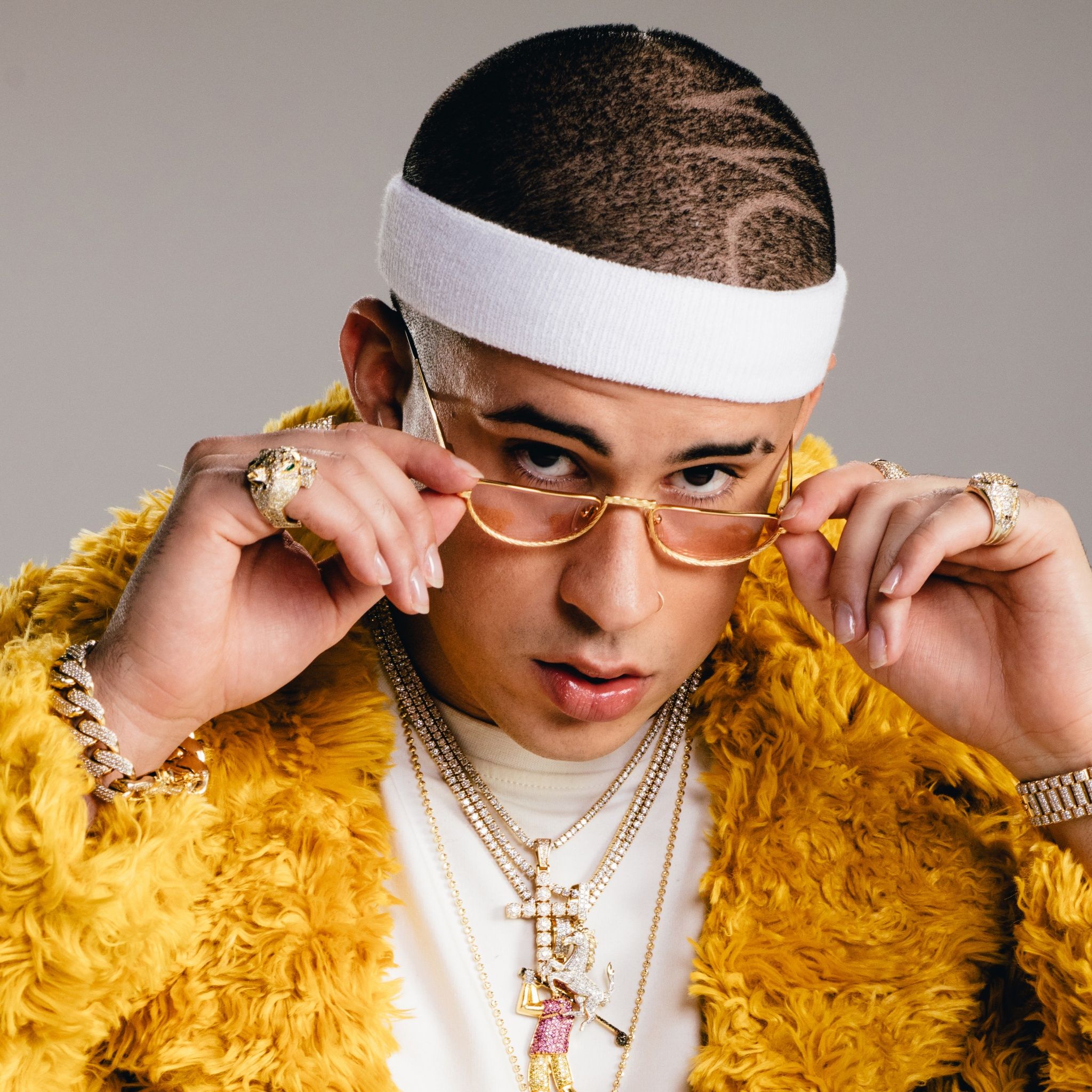 A man wearing sunglasses and yellow clothing - Bad Bunny