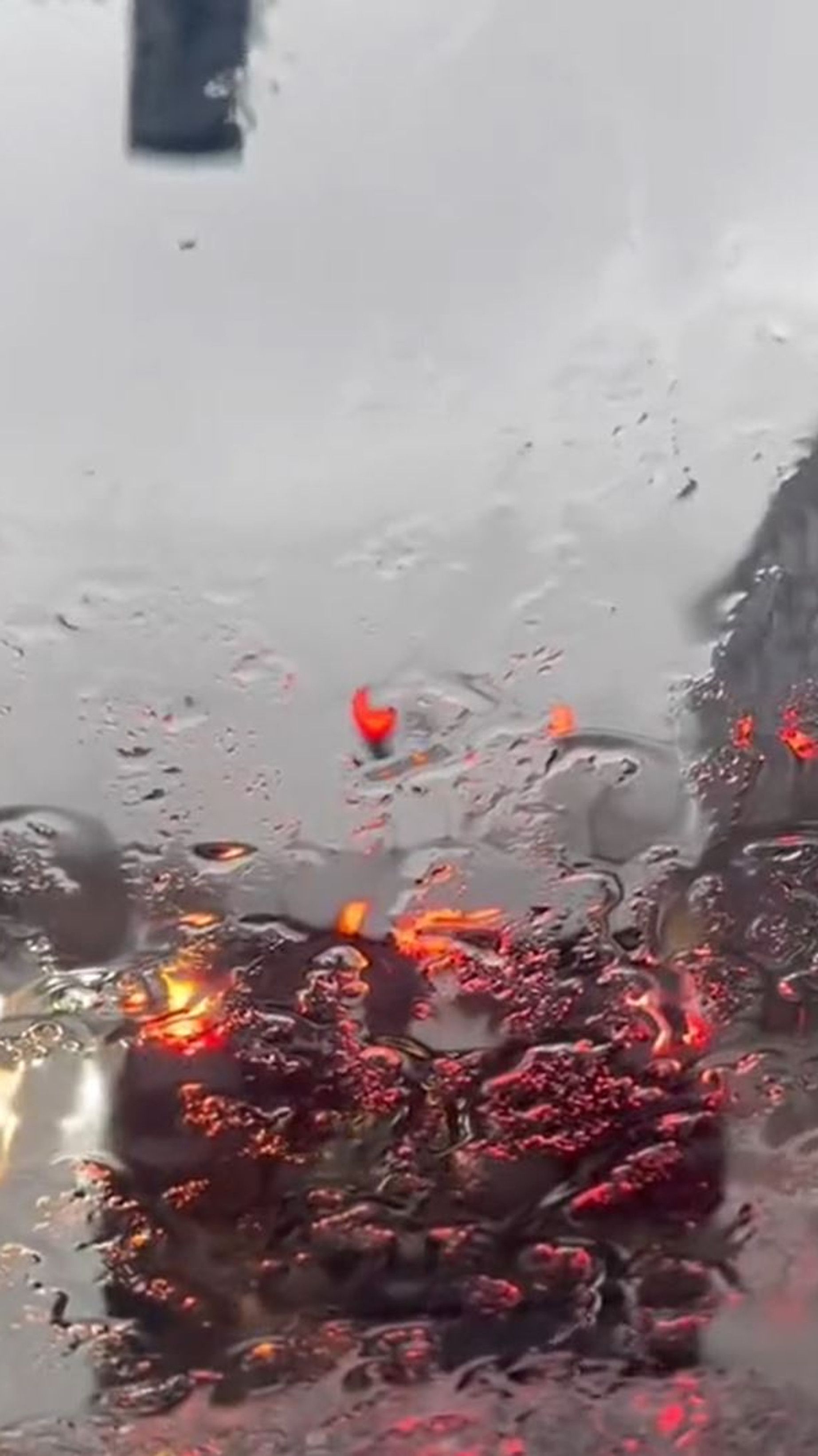 A car is driving through the rain with red lights - Rain