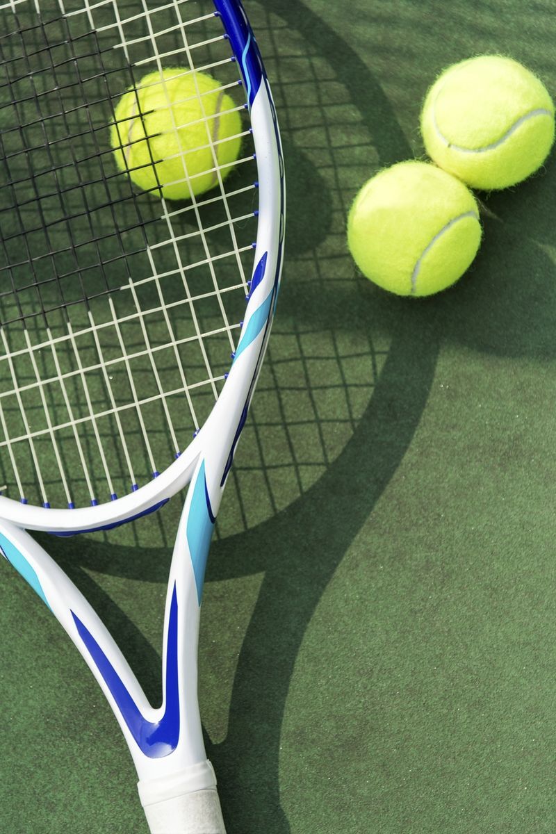 A tennis racket and three balls on the ground - Tennis