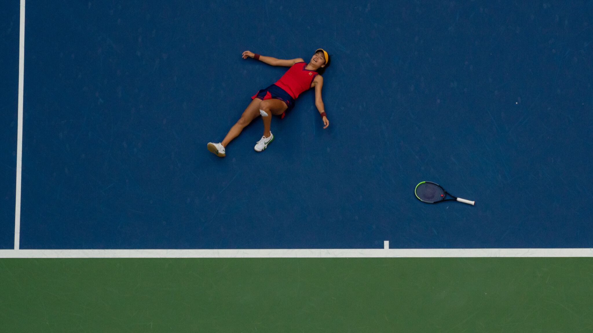 A woman is laying on the tennis court - Tennis