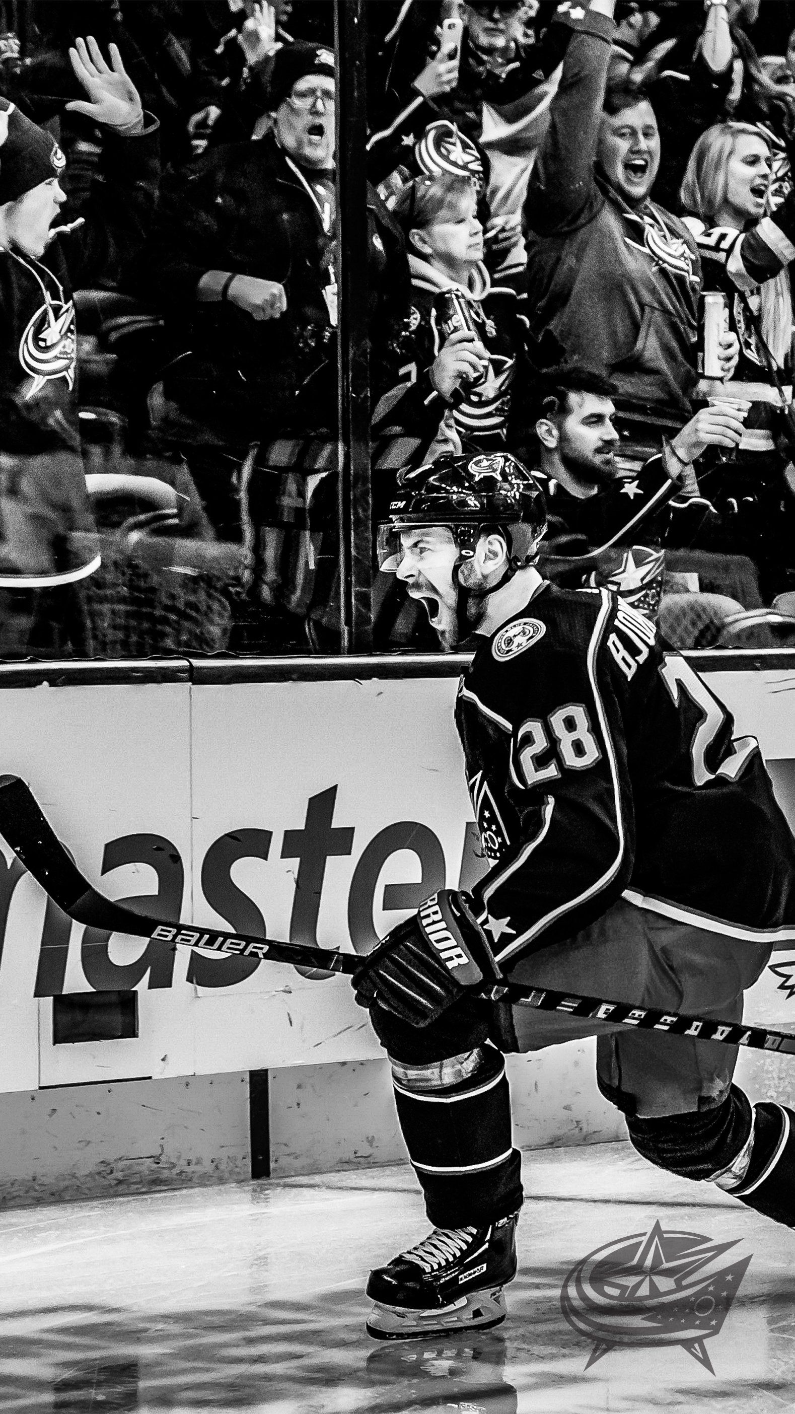 Black and white photo of a hockey player celebrating in front of fans - Black and white