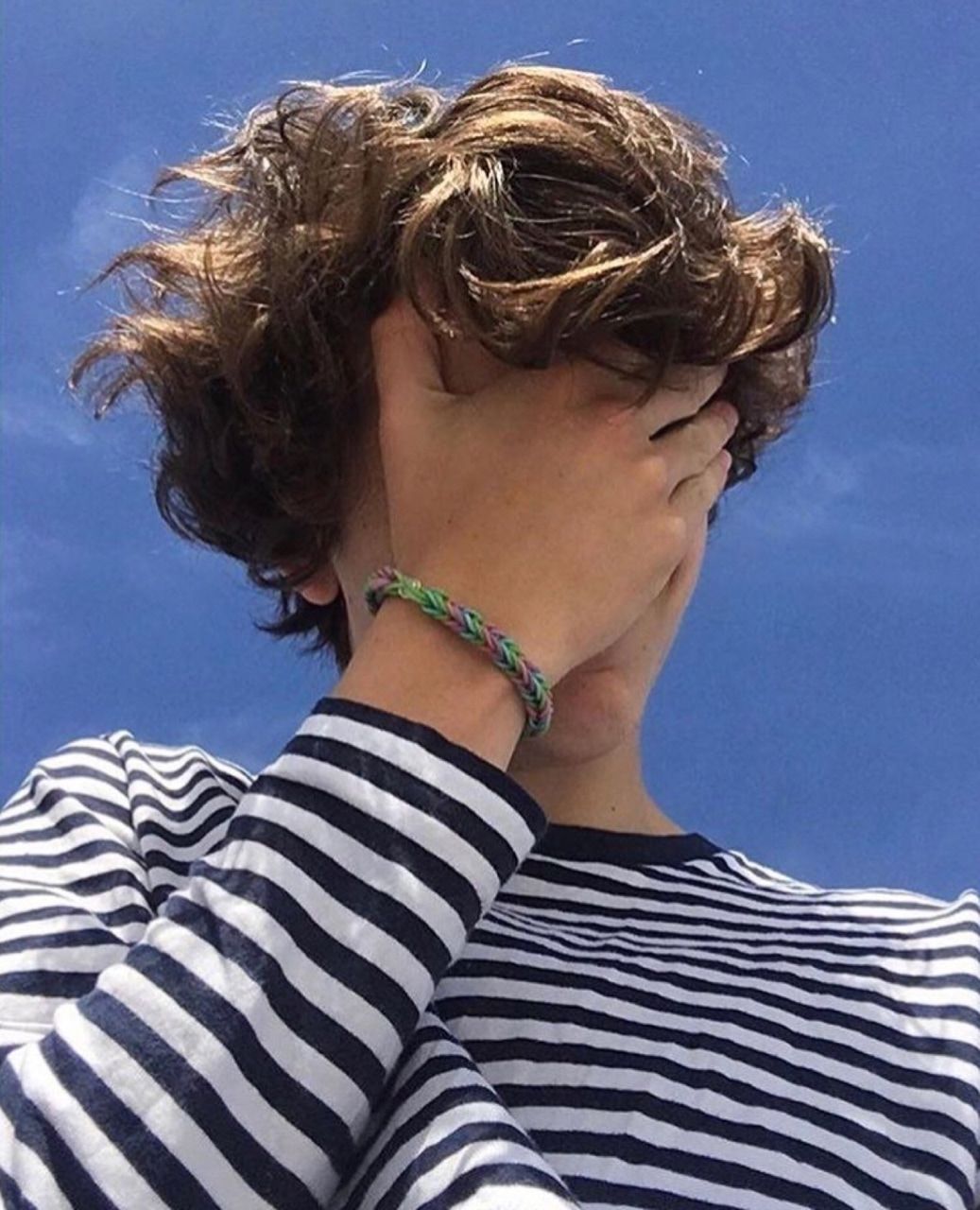 A boy with curly hair covering his face - Timothee Chalamet
