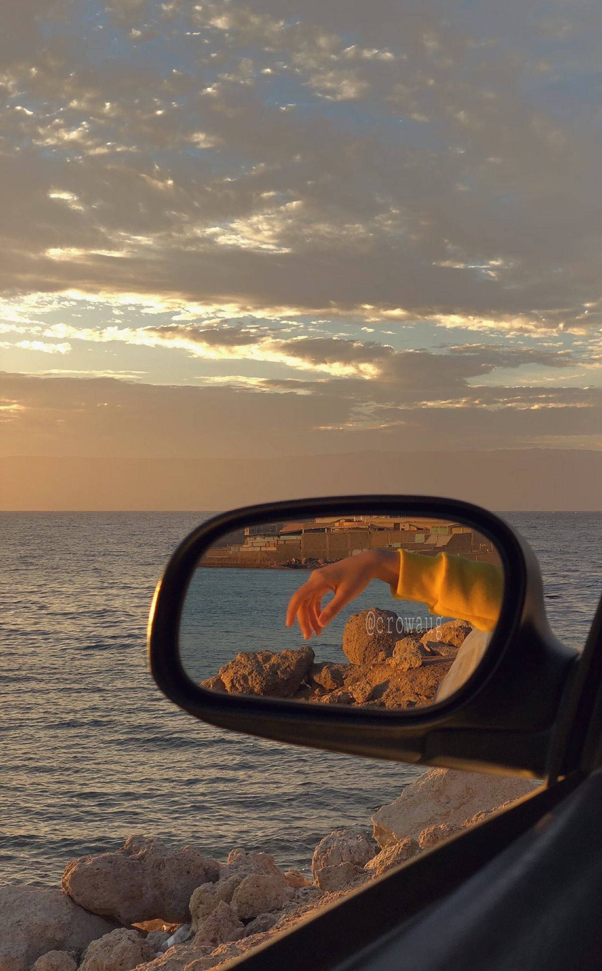 A car mirror shows the reflection of someone's hand - Travel