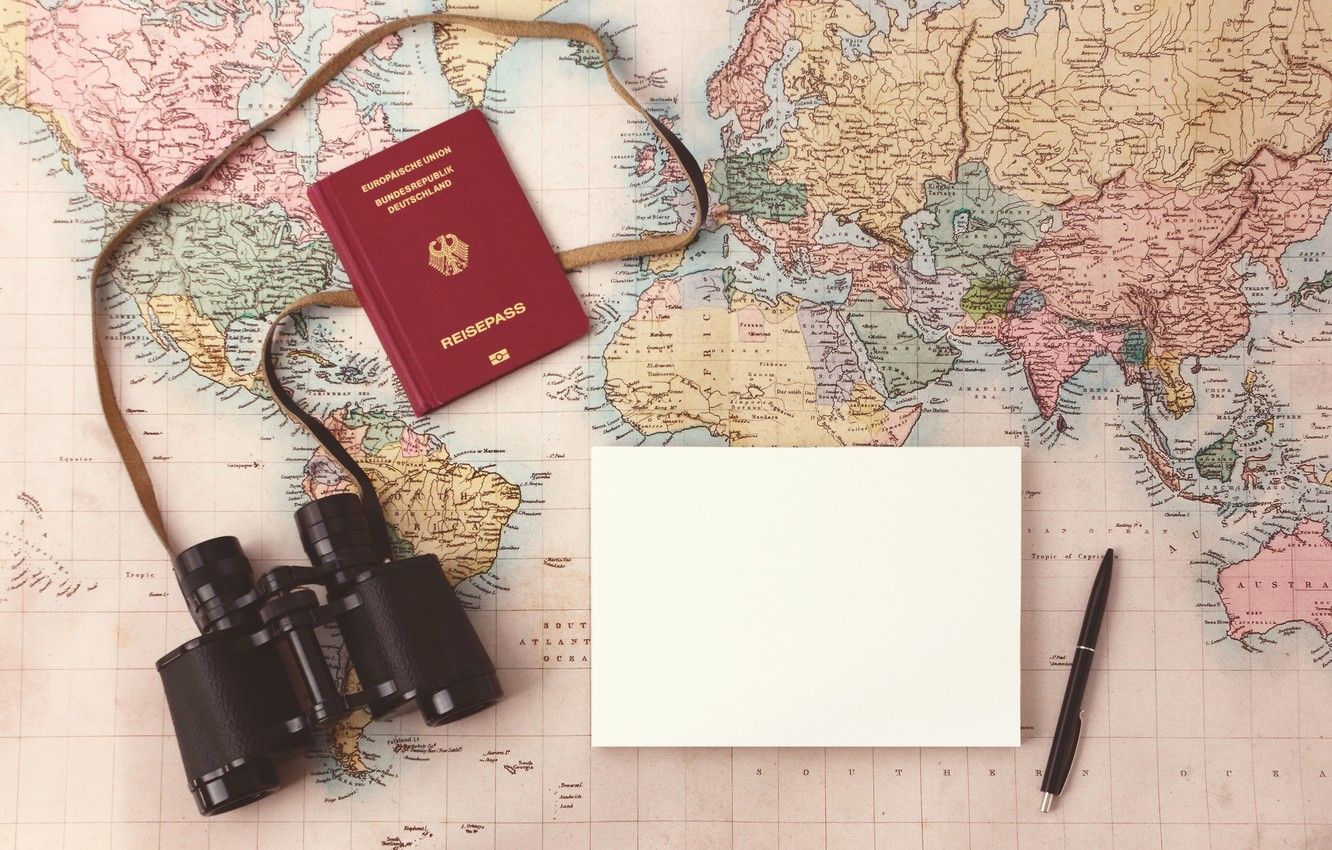 A passport, notebook and pen are on top of an old map - Travel