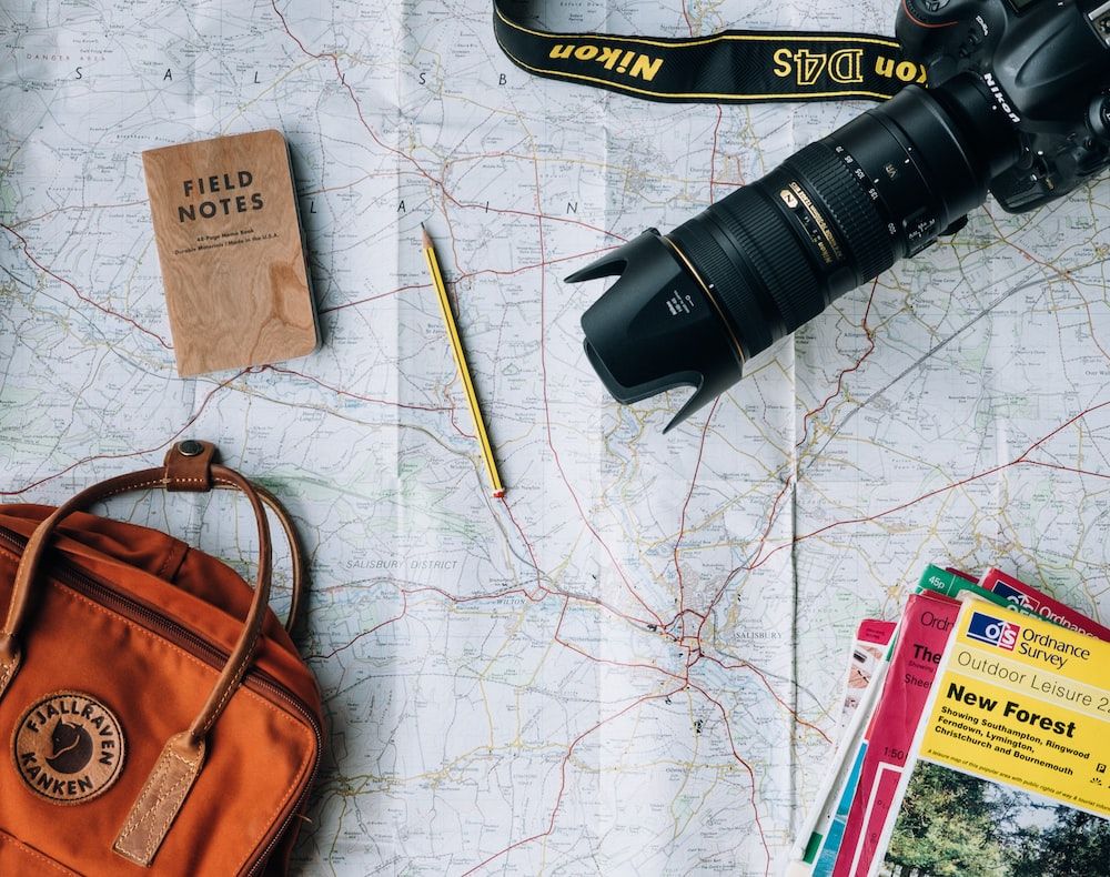 A camera, map and other items are on the table - Travel