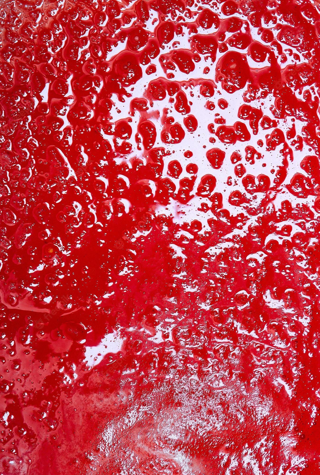 A close up of a red surface with water droplets on it - Blood