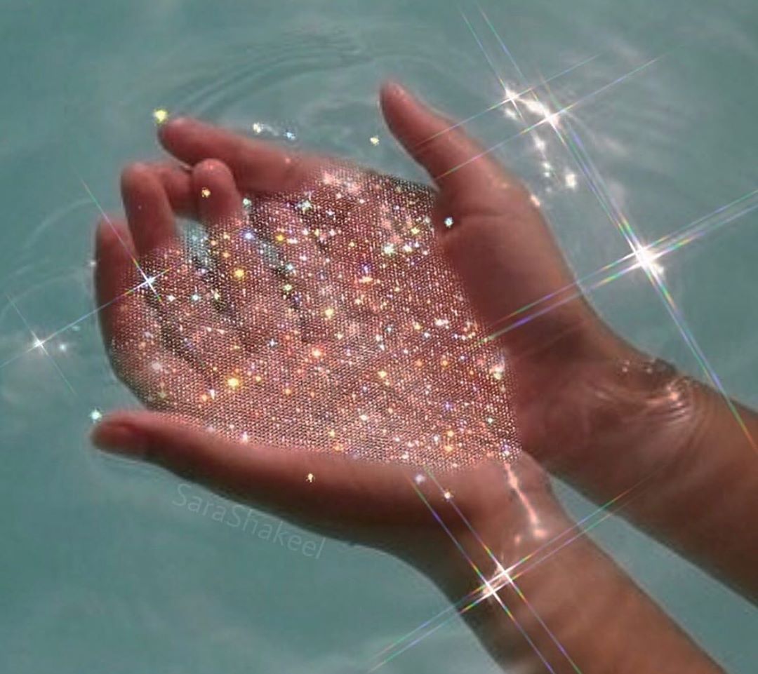 A person holding hands with water and glitter - Water