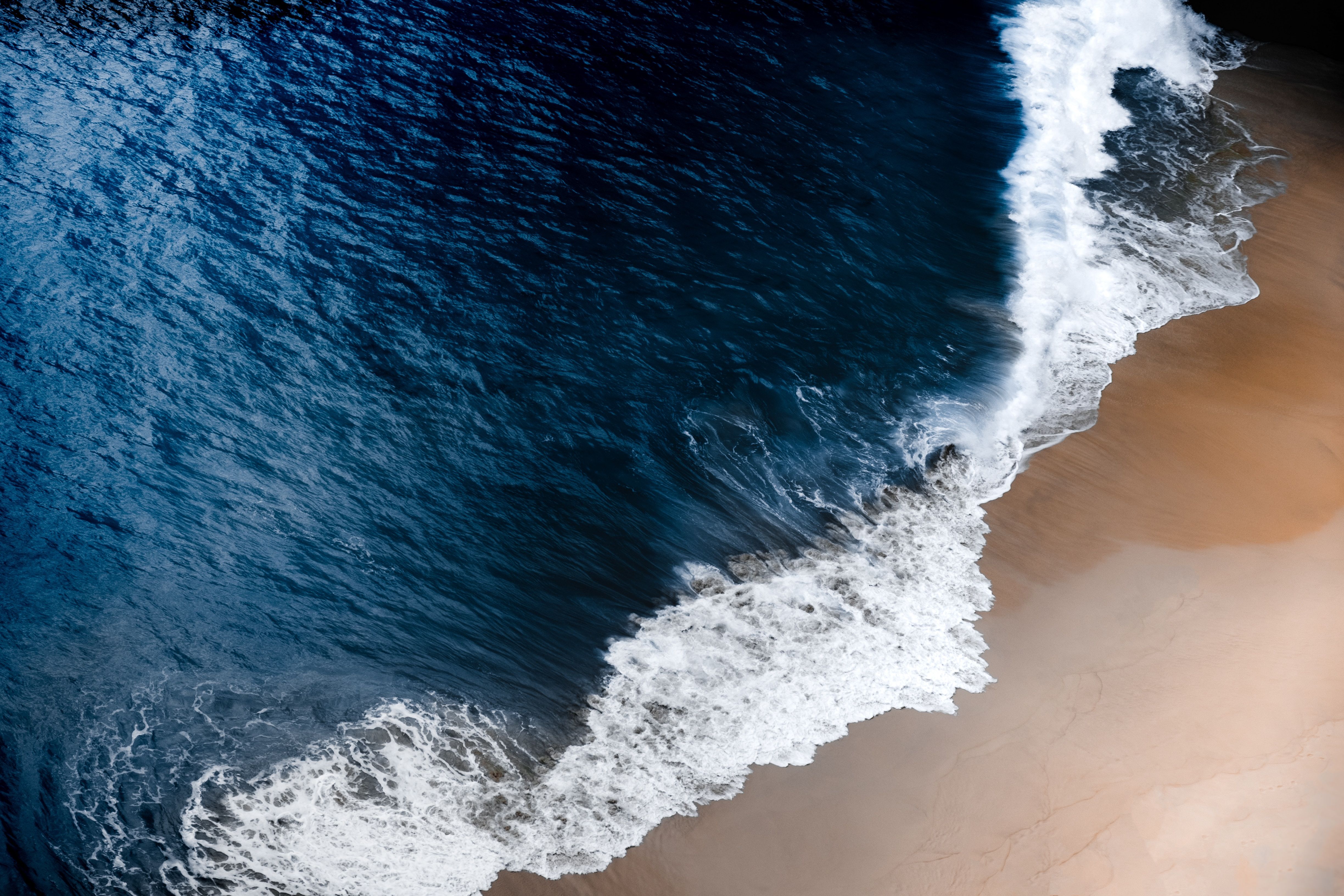 Aerial view of a wave crashing on a beach - Water