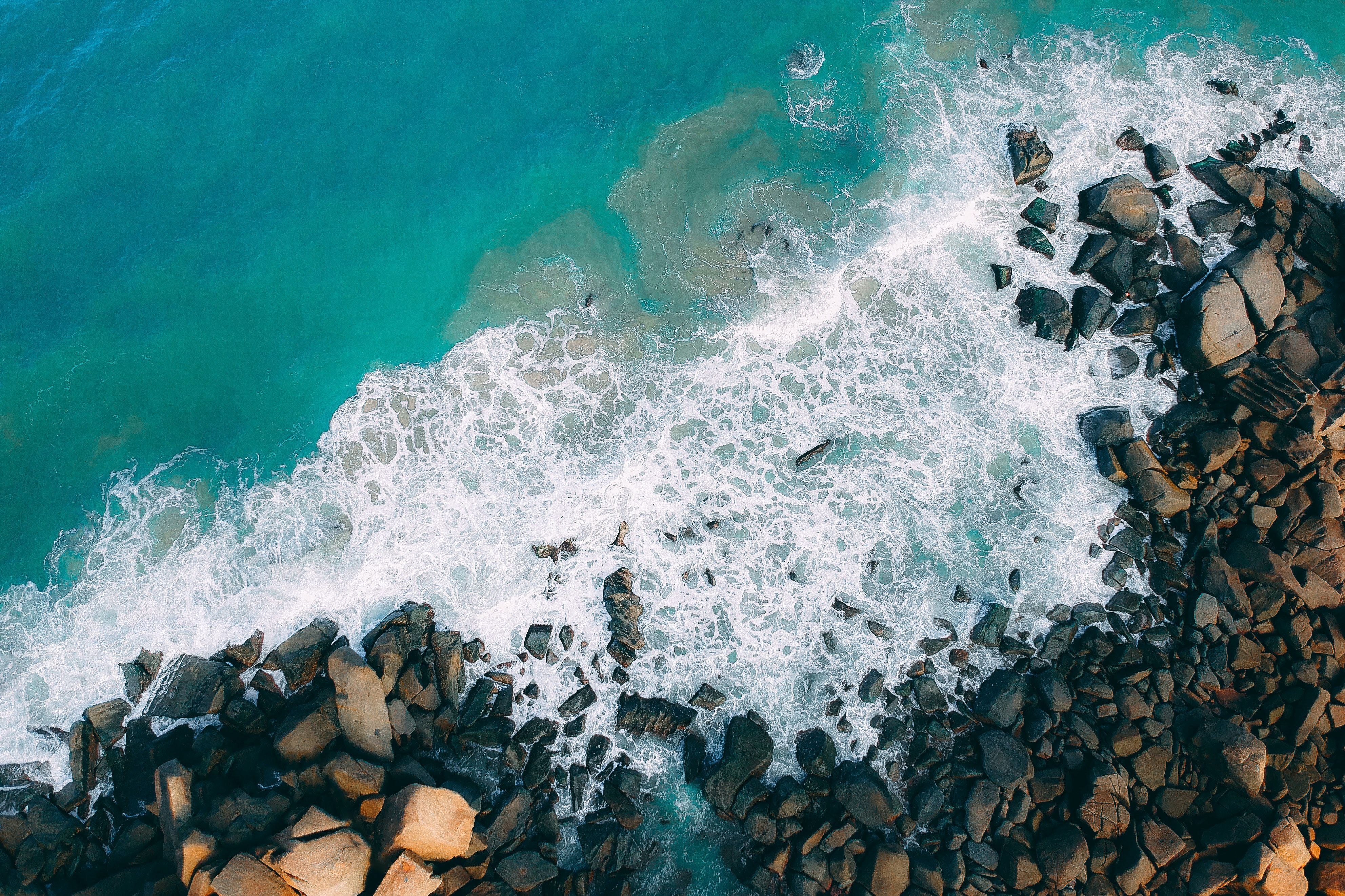 Aerial view of a rocky shoreline with crashing waves - Water