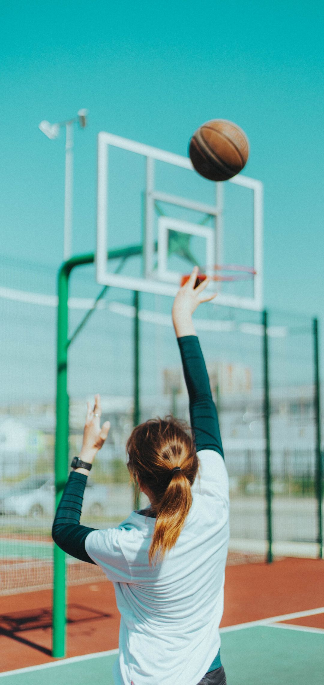 A woman throwing an object at something - Basketball