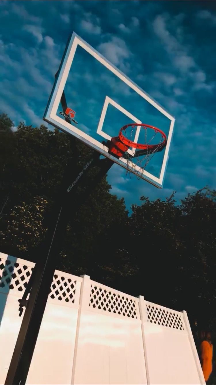 A basketball hoop with a cloudy blue sky in the background - Basketball