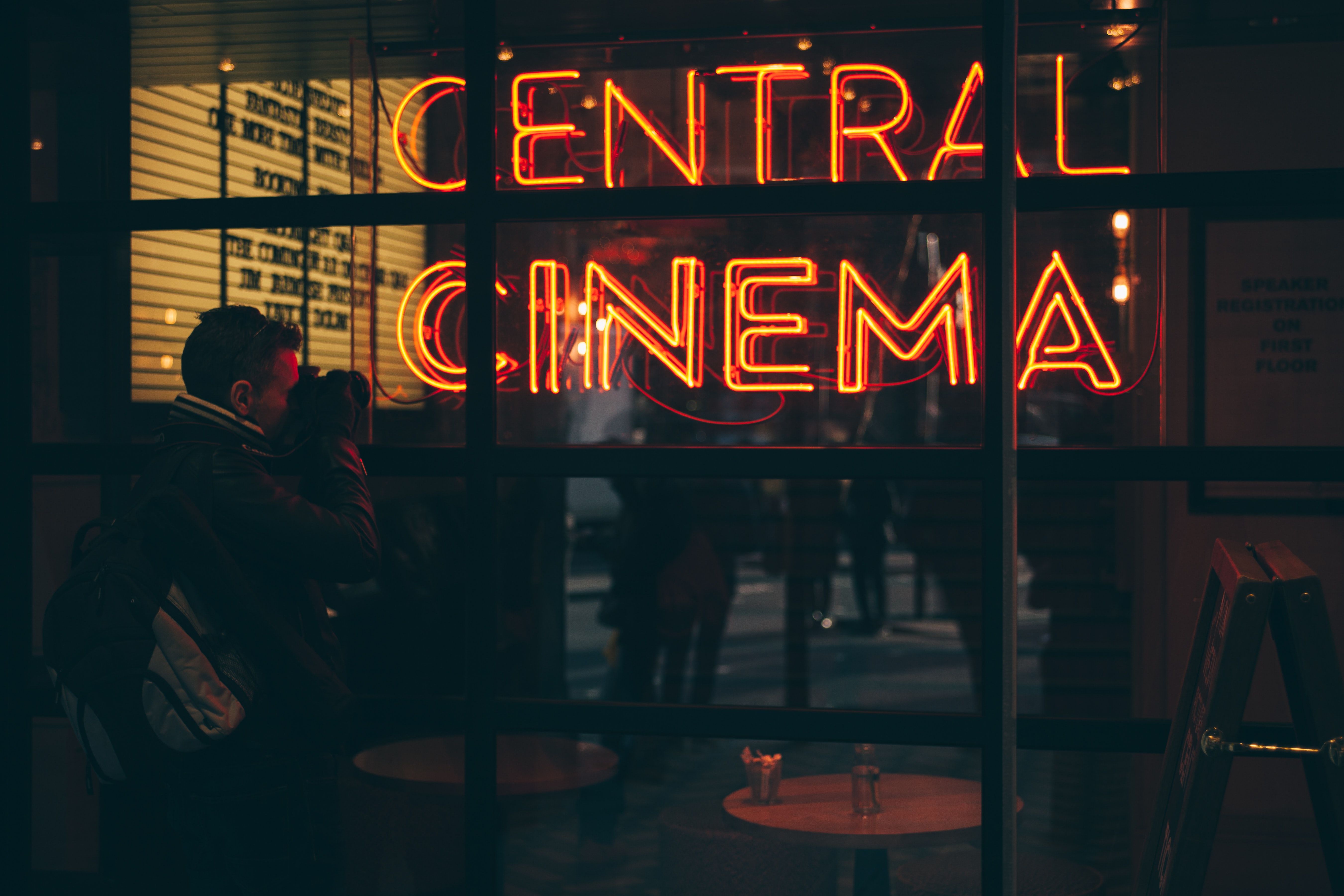 A man is standing in front of the central cinema - Neon orange