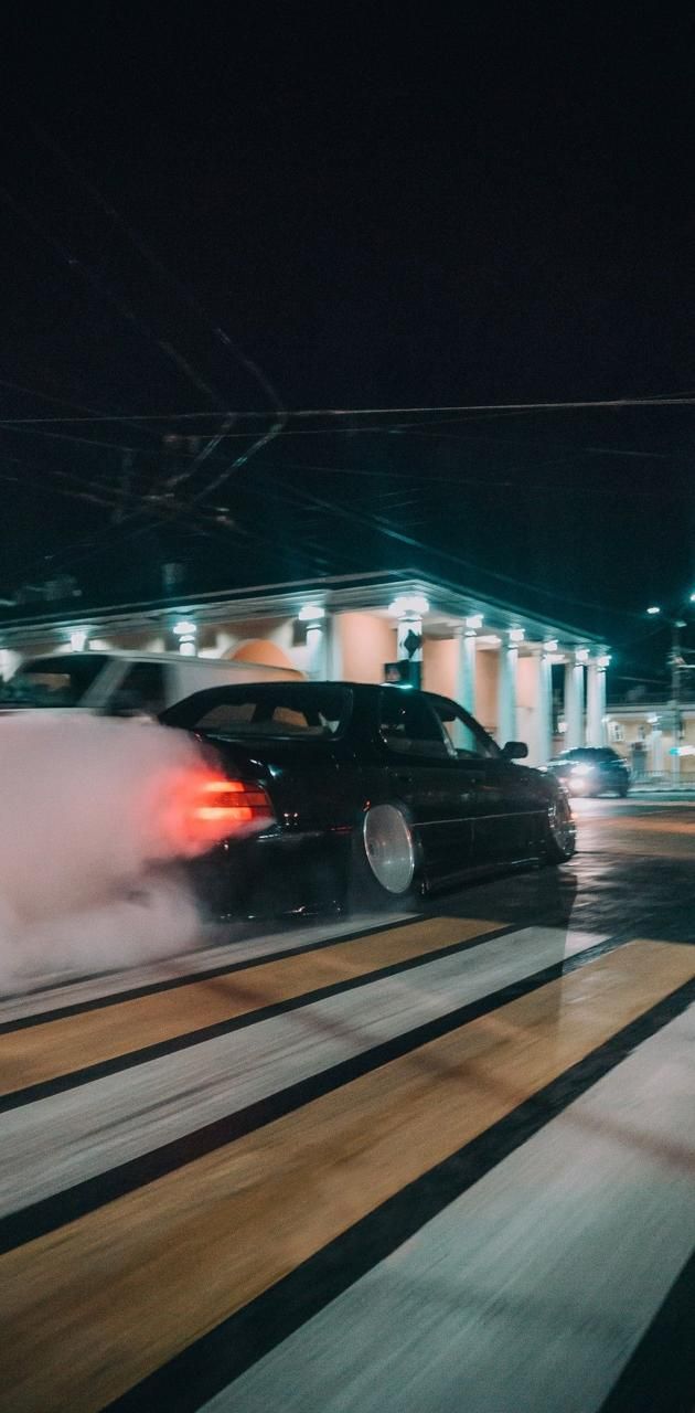 A car is driving down the street with smoke coming out of it - JDM