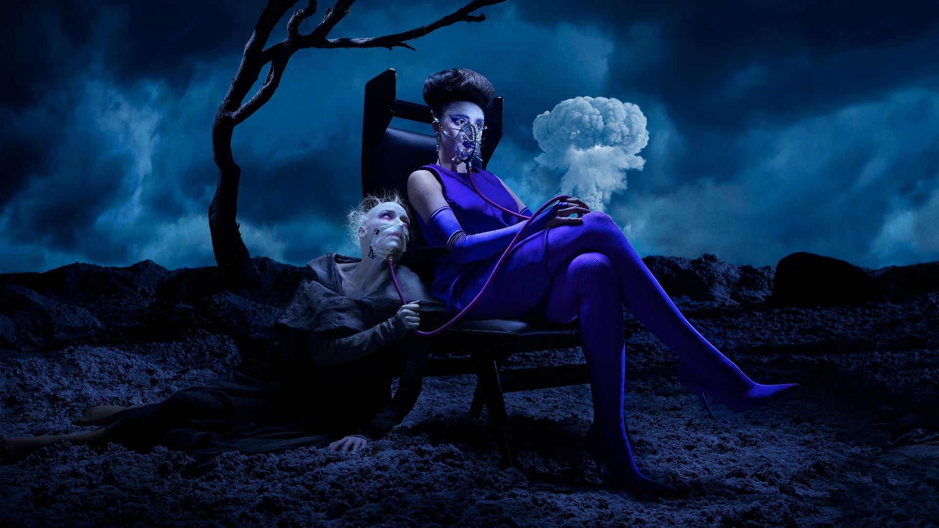 A woman in a purple dress sits on a chair in a dark, rocky landscape. A man kneels at her feet, his face obscured by a mask. - Horror
