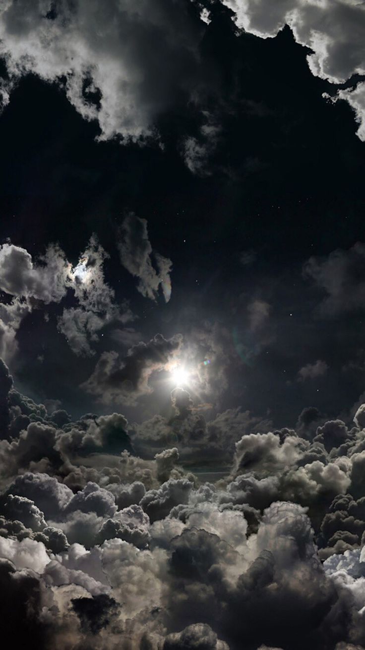 The sun shining through the clouds in the night sky. - Sky