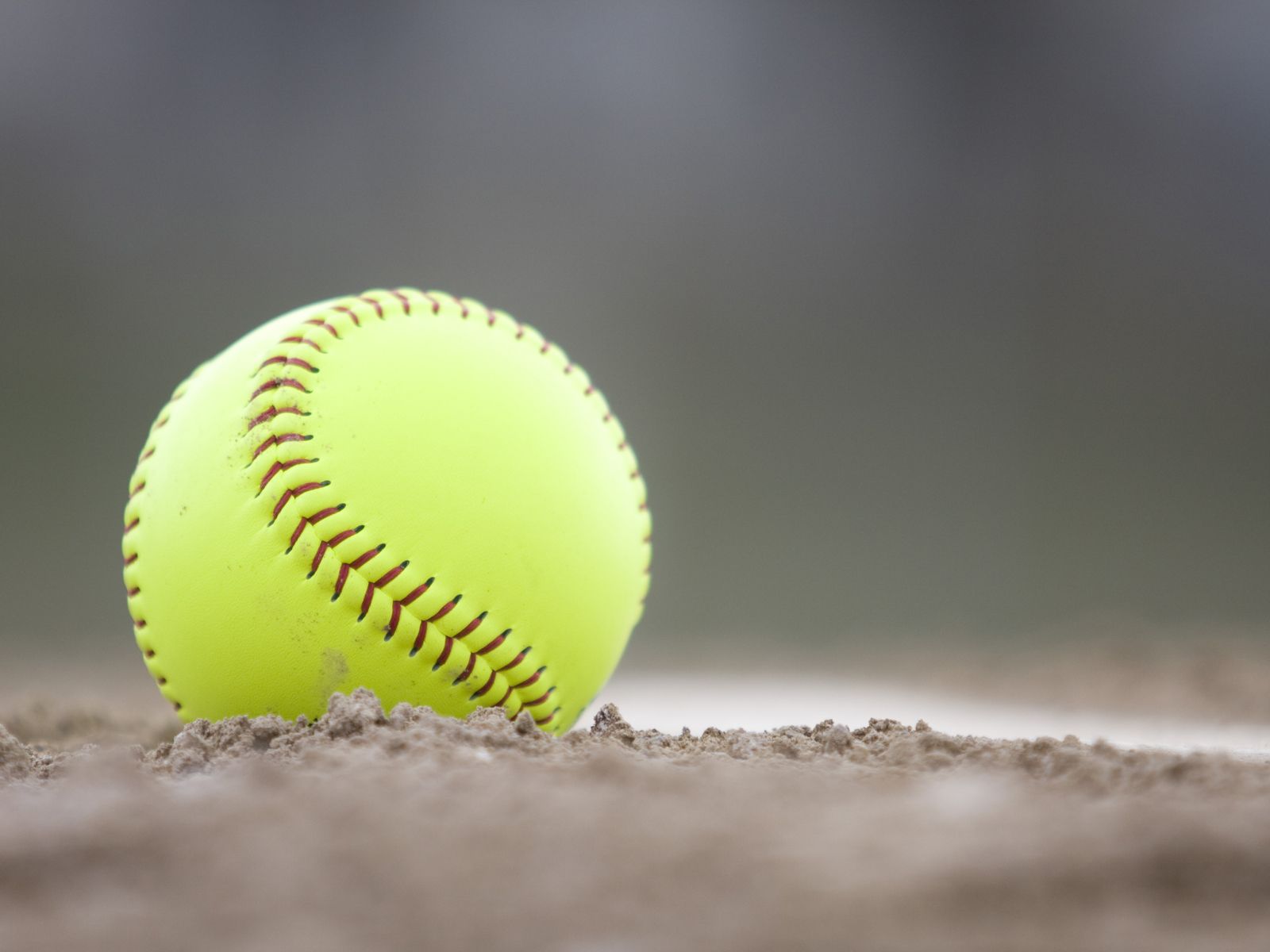 A softball sits on the dirt - Softball