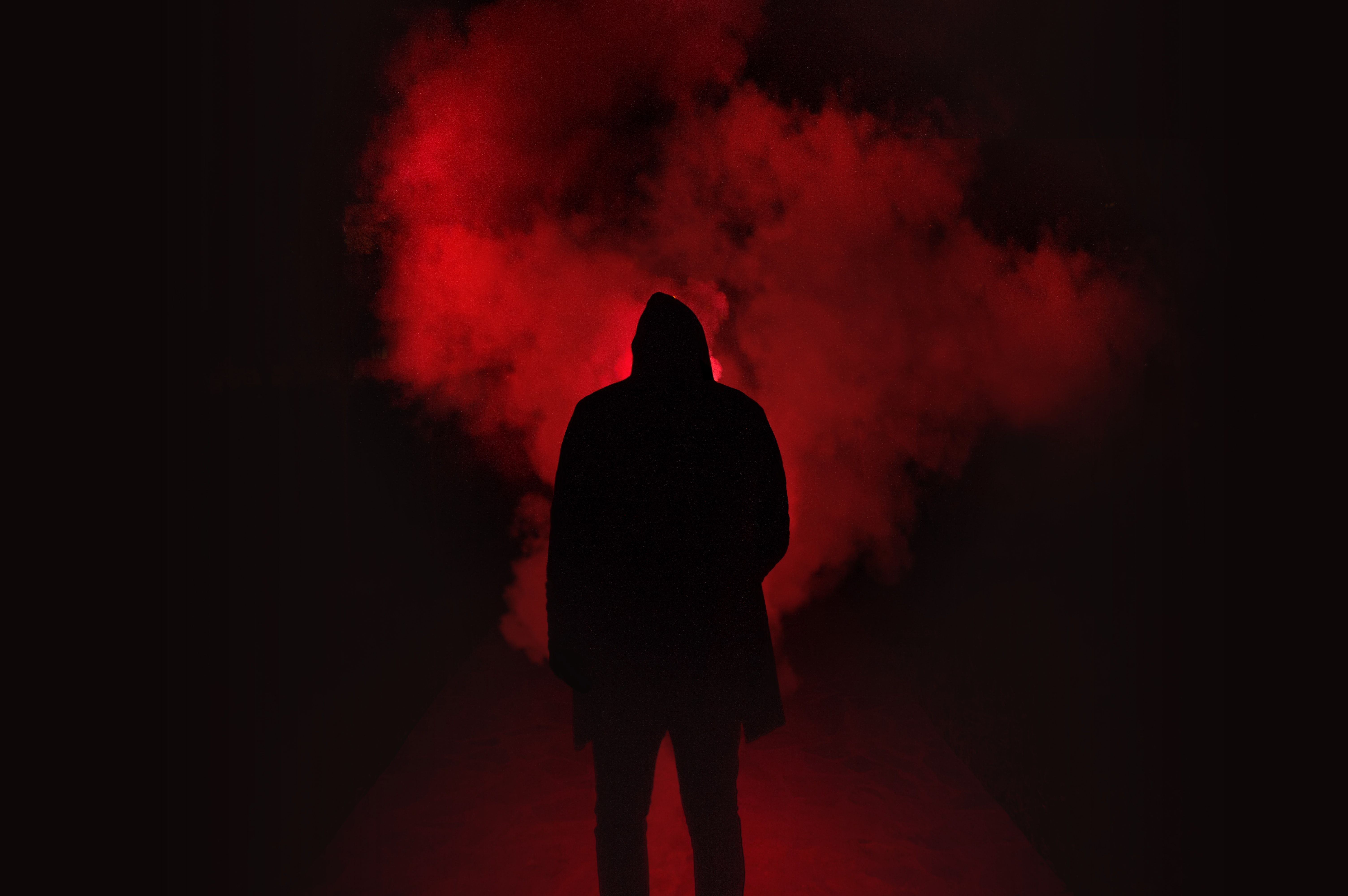 A hooded figure stands in a red smog. - Smoke