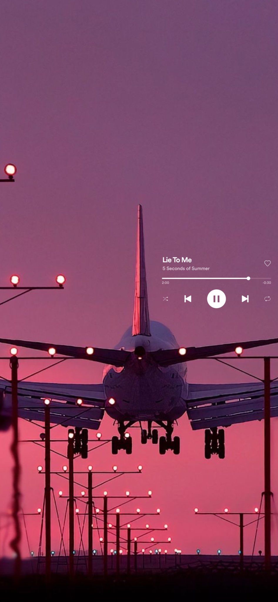 IPhone wallpaper of a plane landing at sunset with a song playing - Spotify