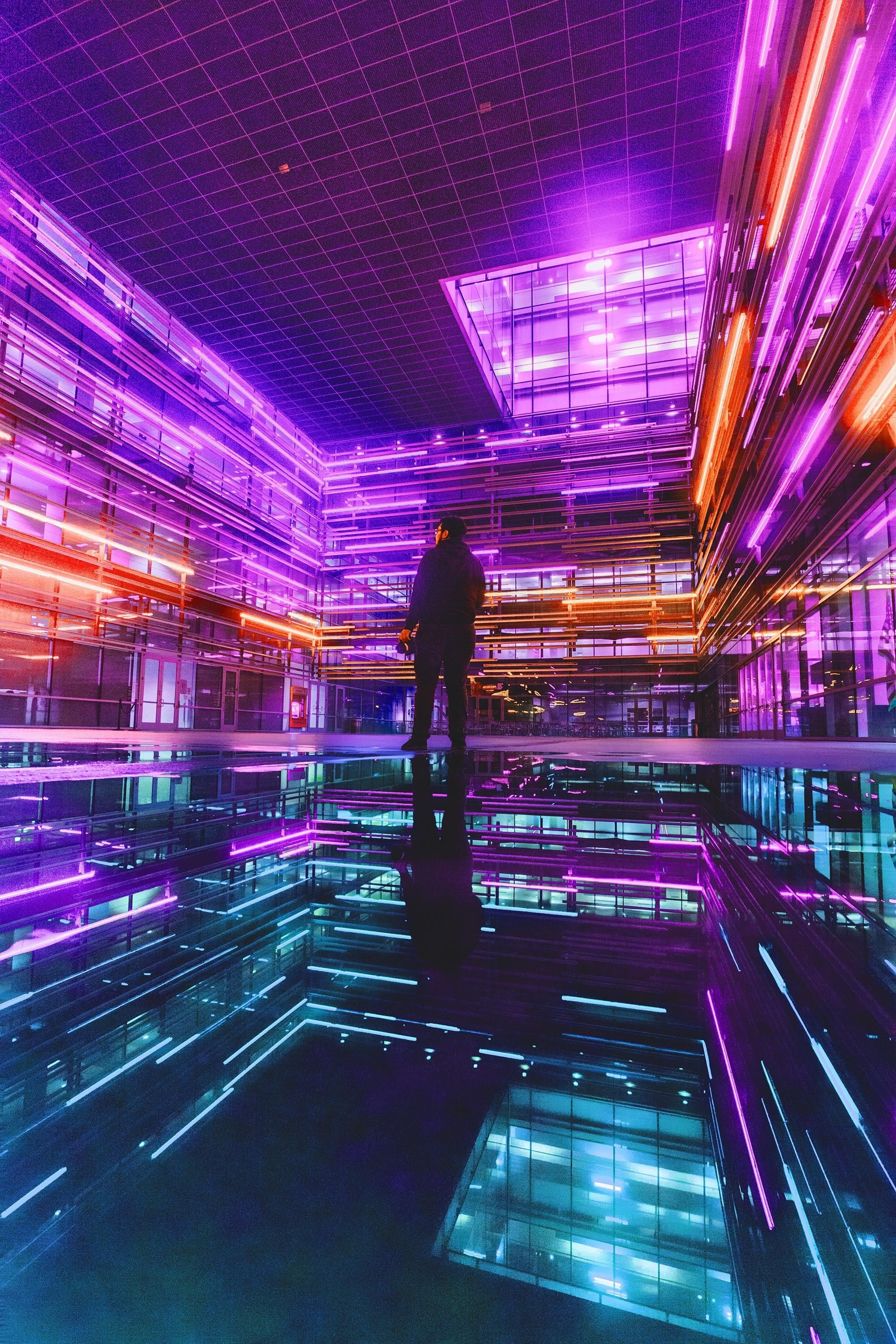 A person standing in front of an illuminated building - Neon