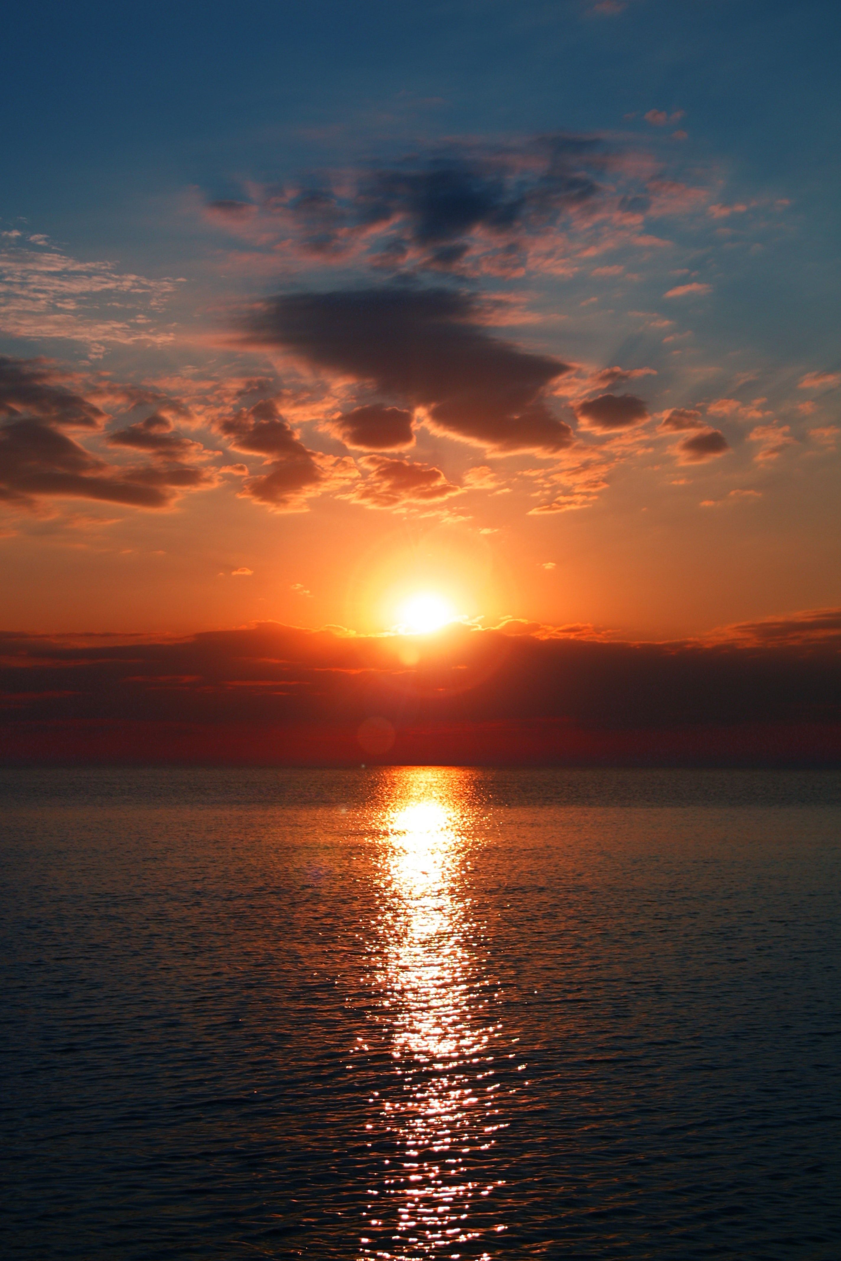 A sunset over the ocean with clouds - Sun