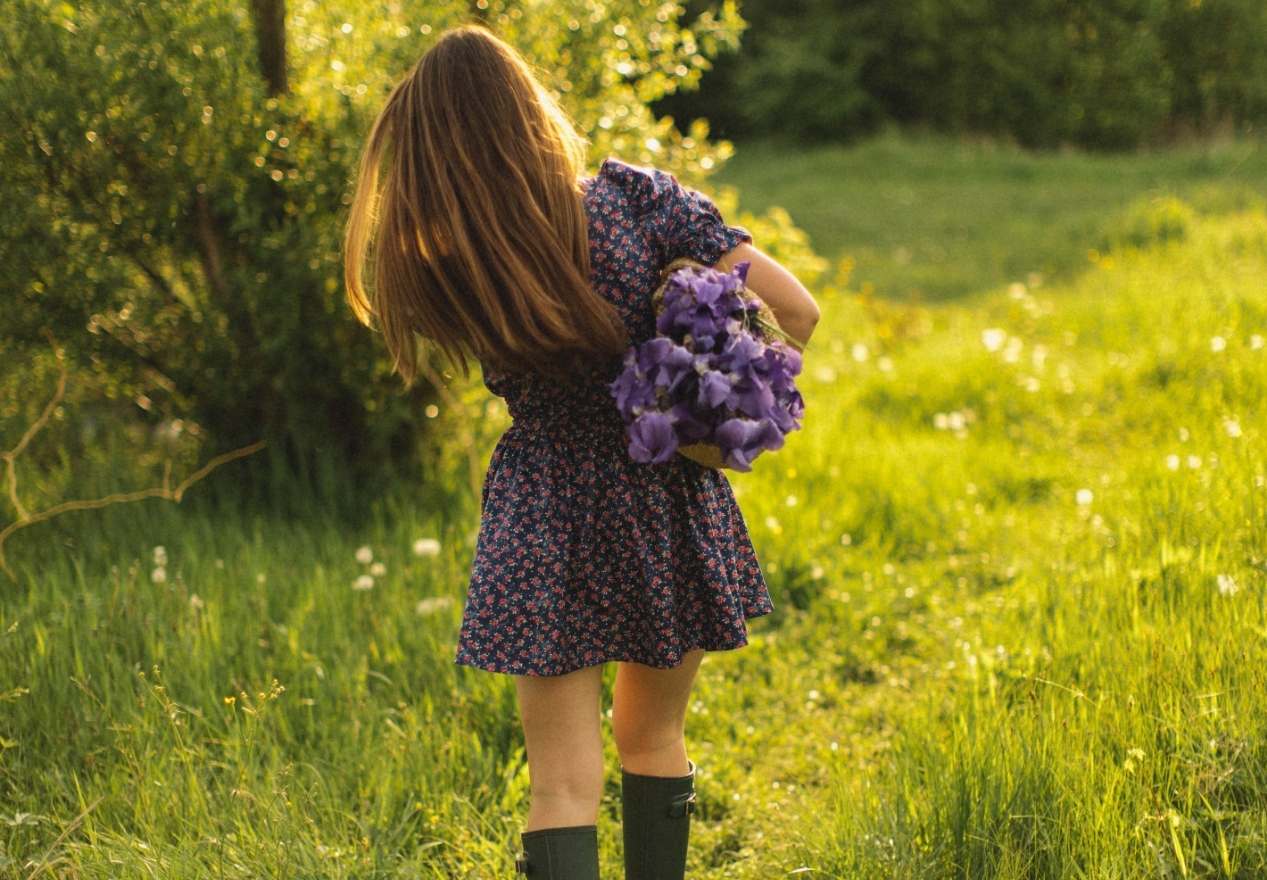 A woman holding a bouquet of purple flowers in a field. - Cottagecore, farm