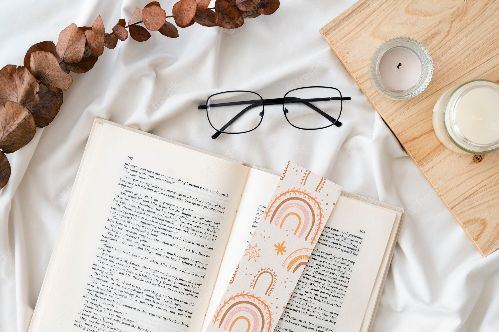 Open book with glasses and a candle on a white sheet - Books