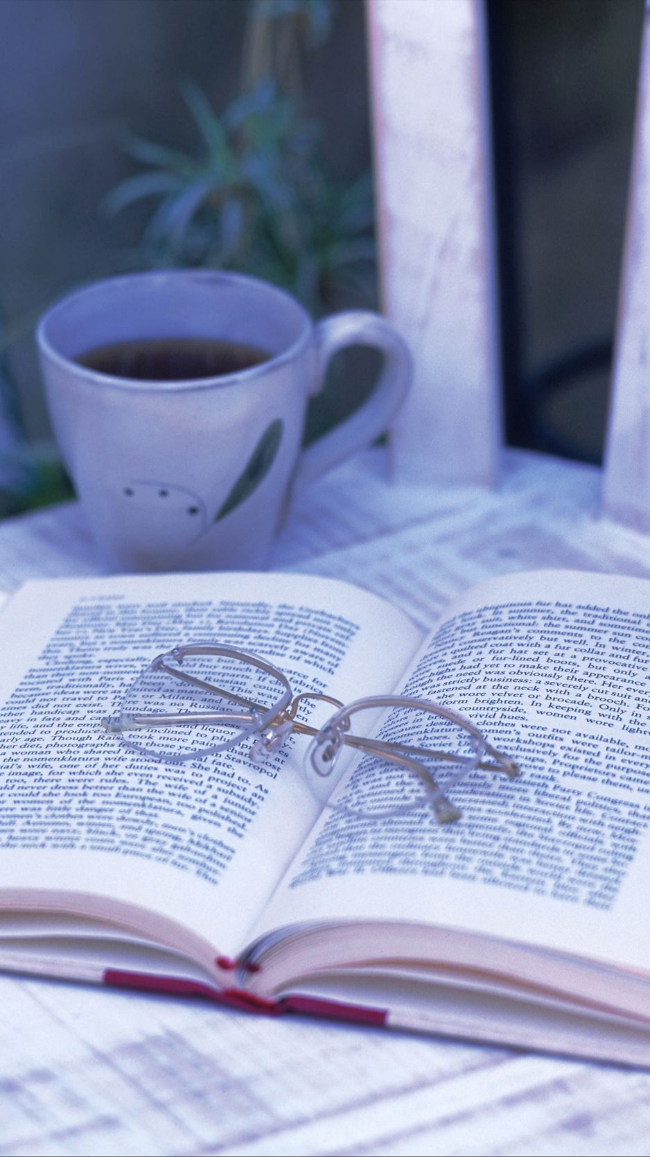 Open book with glasses on top and a cup of coffee next to it - Books